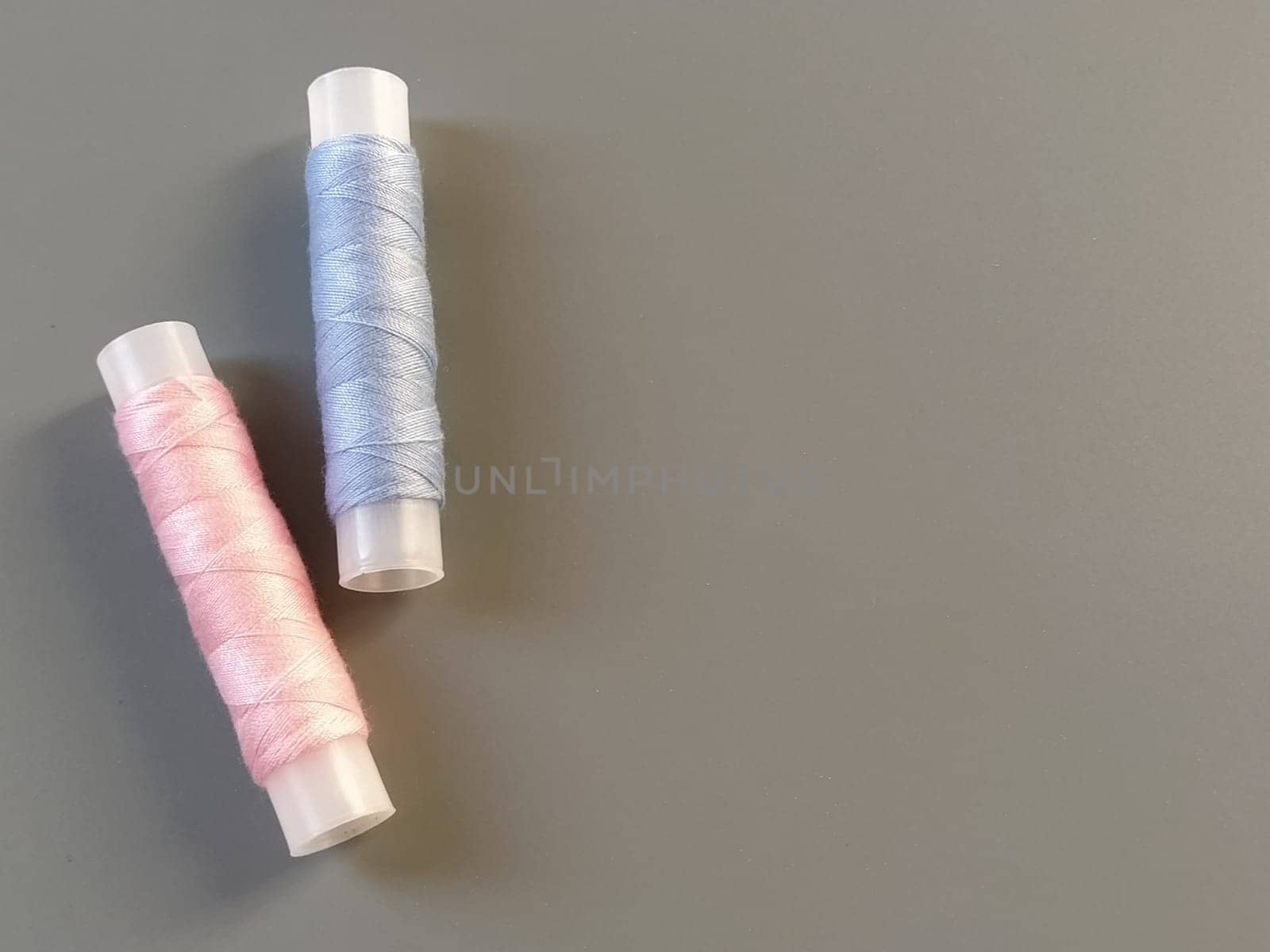 Spools of pink and blue thread on a gray background. Textile industry.