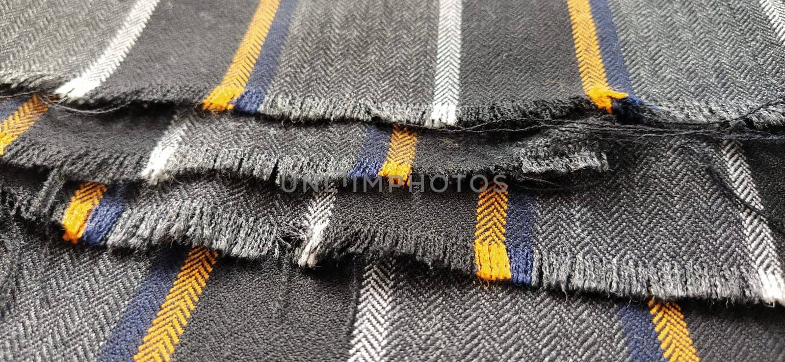 Gray-black fabric with orange and blue stripes. Textile fabric folded neatly on the surface. Natural wool material for sewing clothes and upholstery. Lifestyle. Close-up. Soft focus.