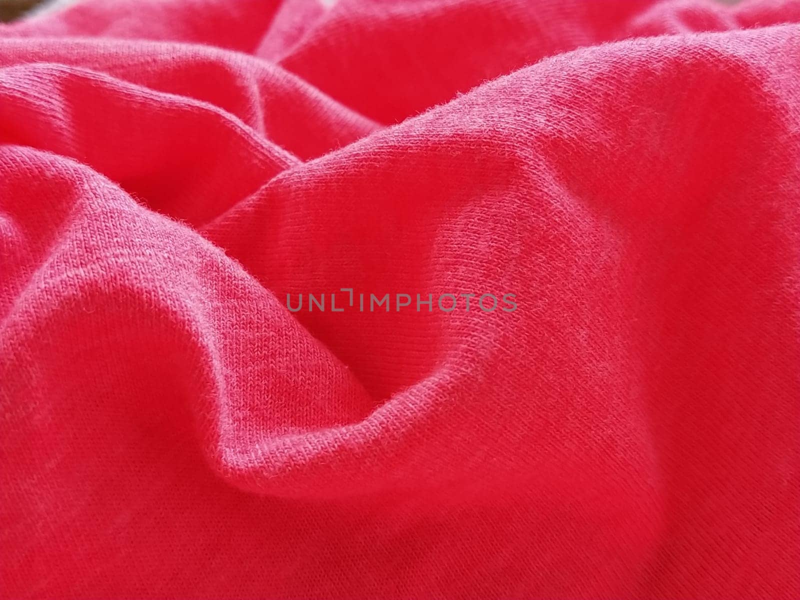 Bright pink or magenta polyester fabric, wrinkled or folded carelessly. Saturated background. Defocused photo around the edges of the photo