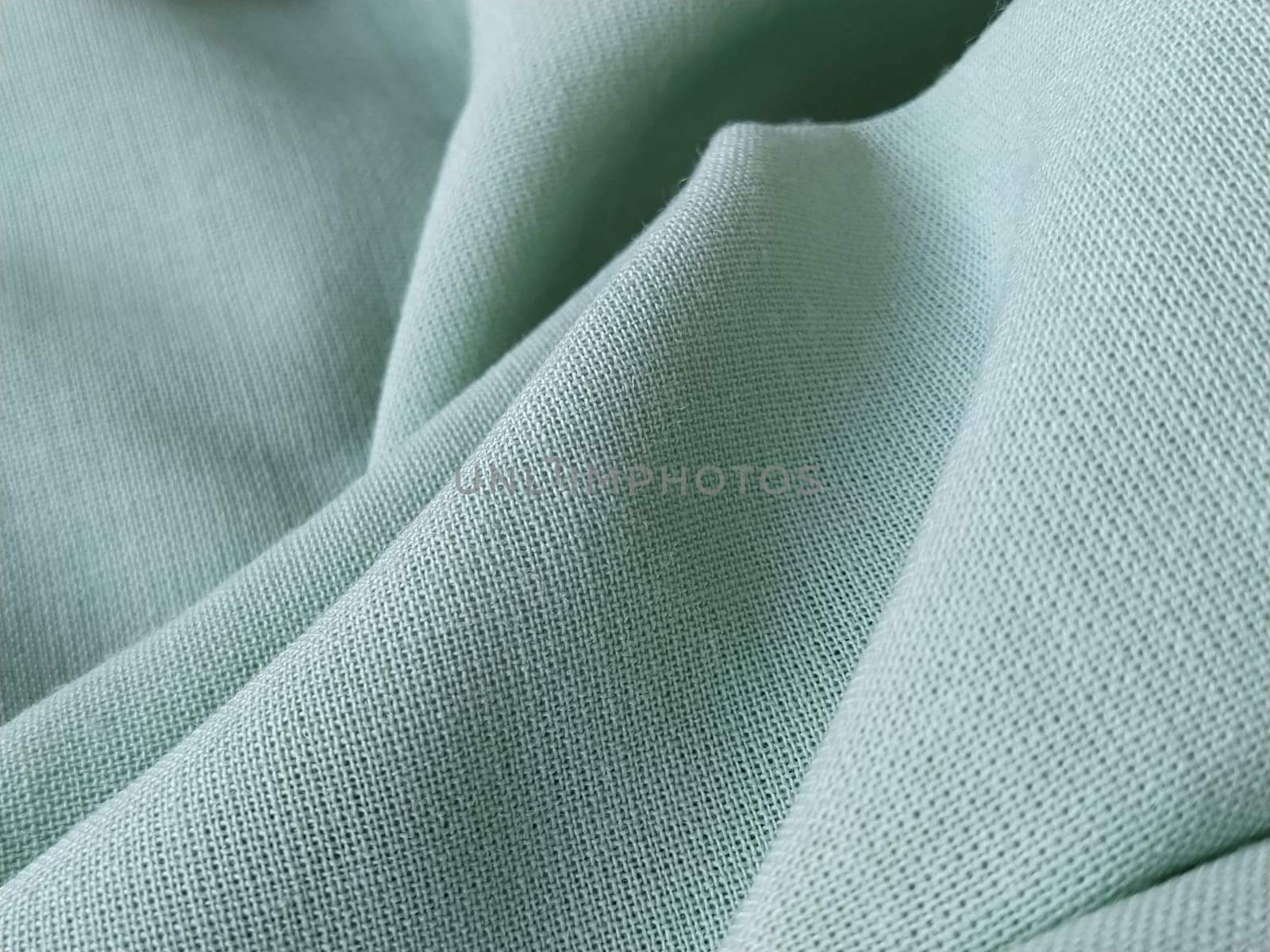 Close up of a woolen fabric of green color. Abstract canvas background, empty template. Thin natural fabric, wool or linen.