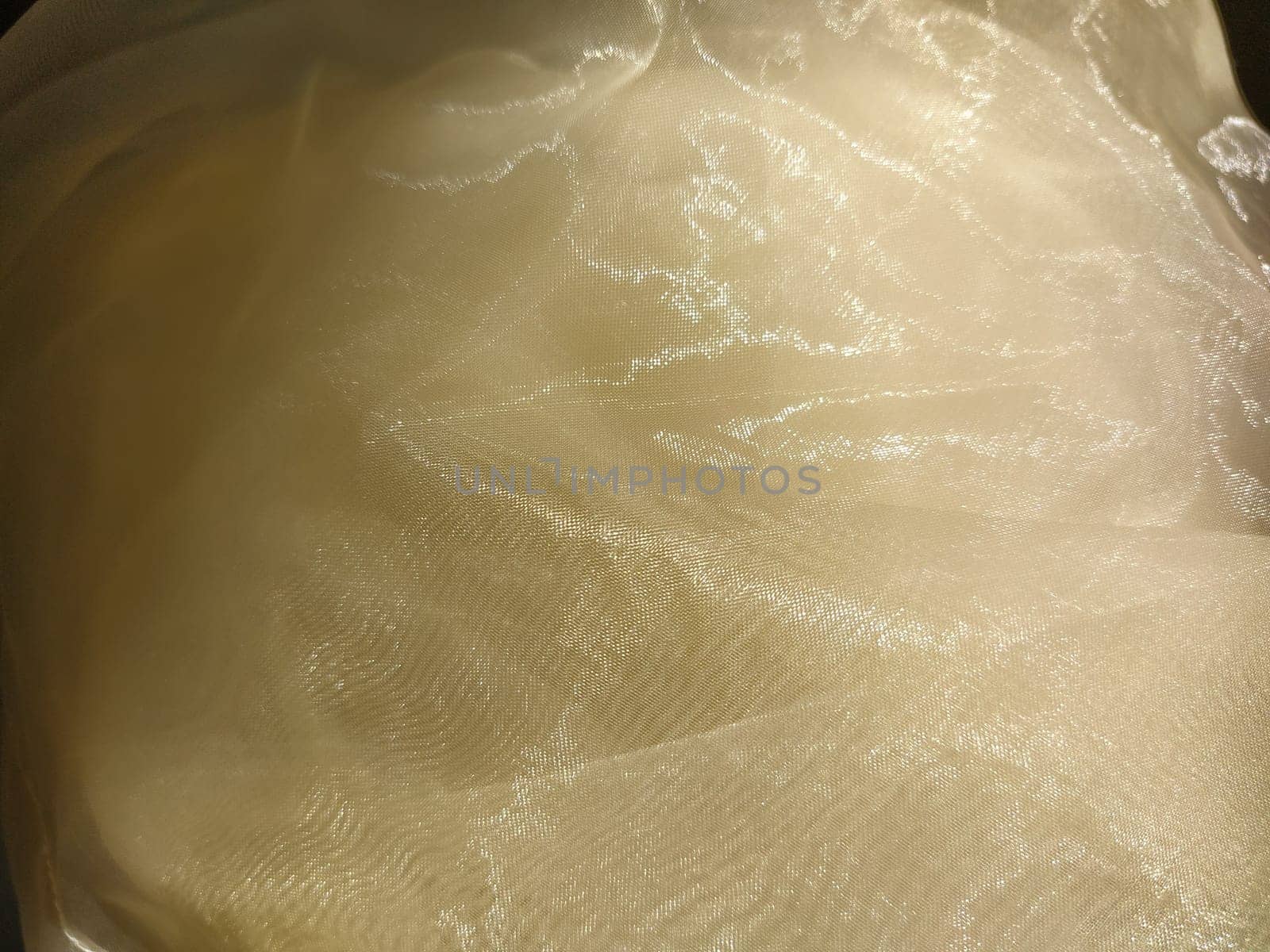 Organza in white and beige or champagne color close-up. Lightweight sheer tulle curtains under side lighting.