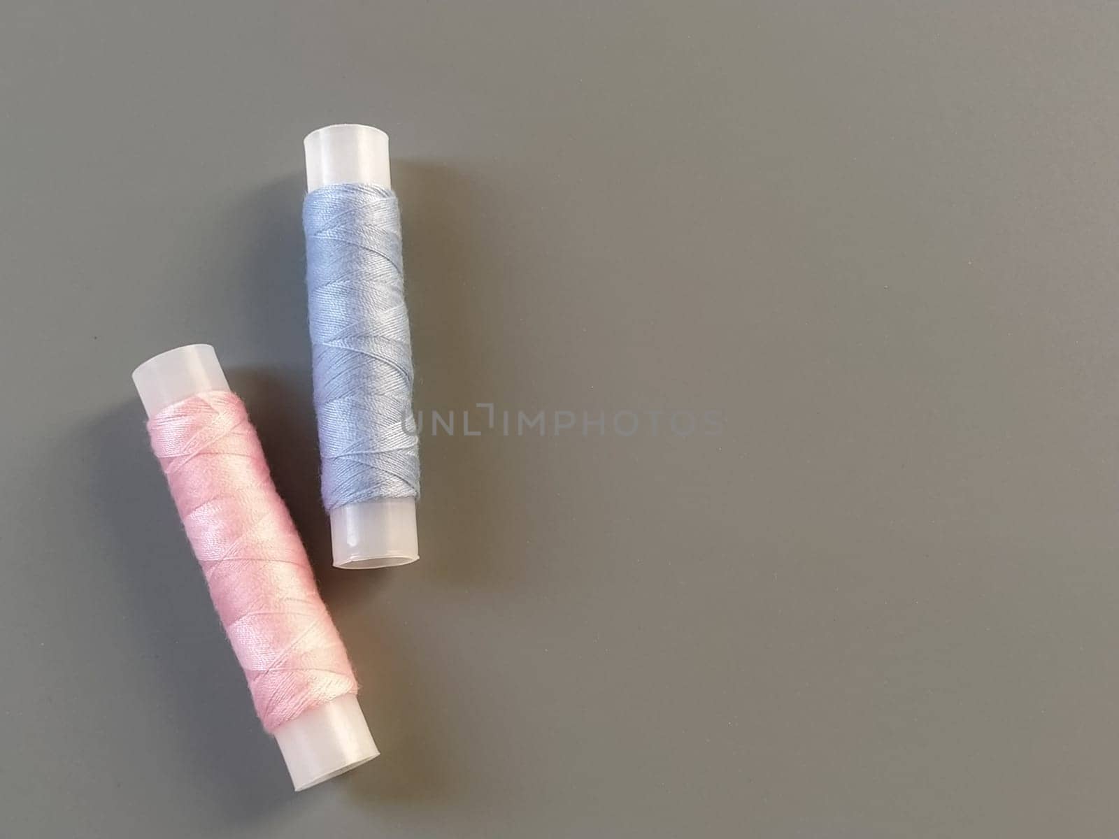Spools of pink and blue thread on a gray background. Textile industry.