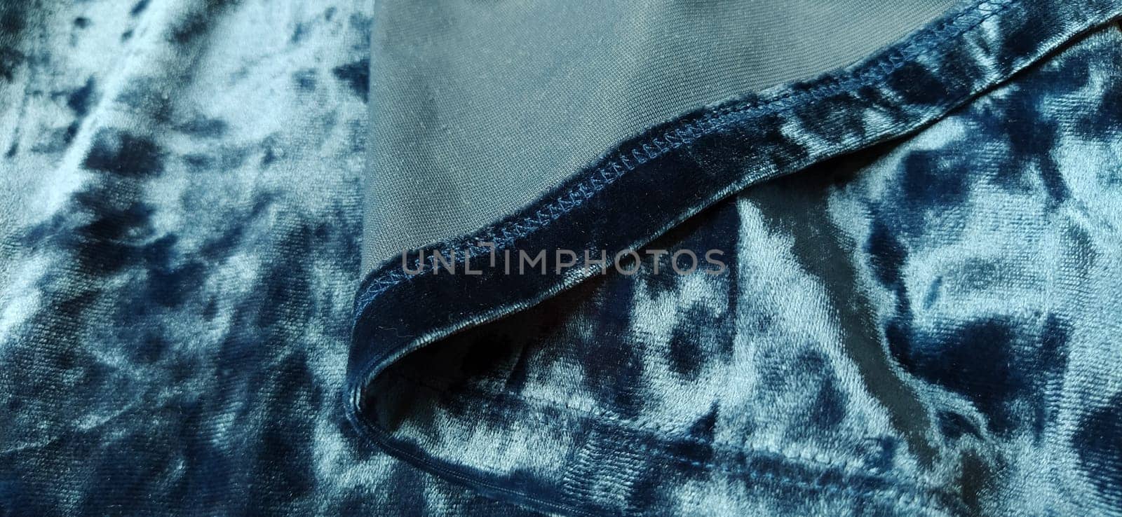Velvet velor cloth background with glowing light and dark shadows. Background for theater and fashion design themes. Nice blue fabric with overflow.