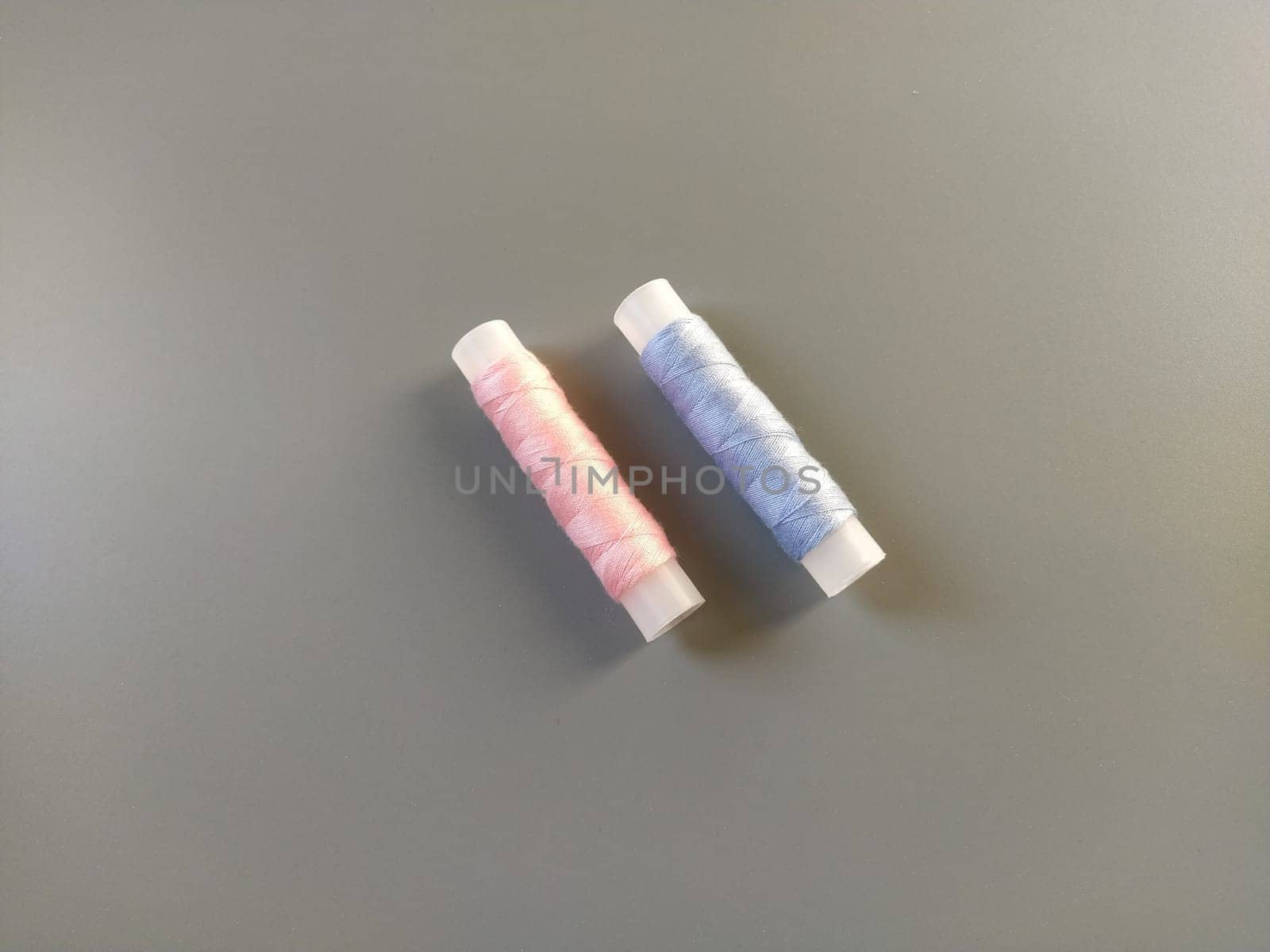 Spools of pink and blue thread on a gray background. Textile industry.
