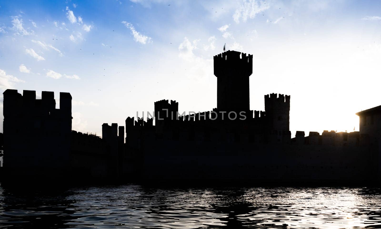 Italy - Sirmone castle silhouette on the Garda lake at sunset. Medieval architecture with tower