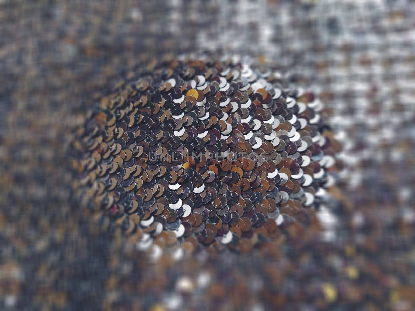 Sequin fabric. Black sequins with white-gray tint. Reflection of light on individual elements in a chaotic manner. Blurred circle background. Soft focus.