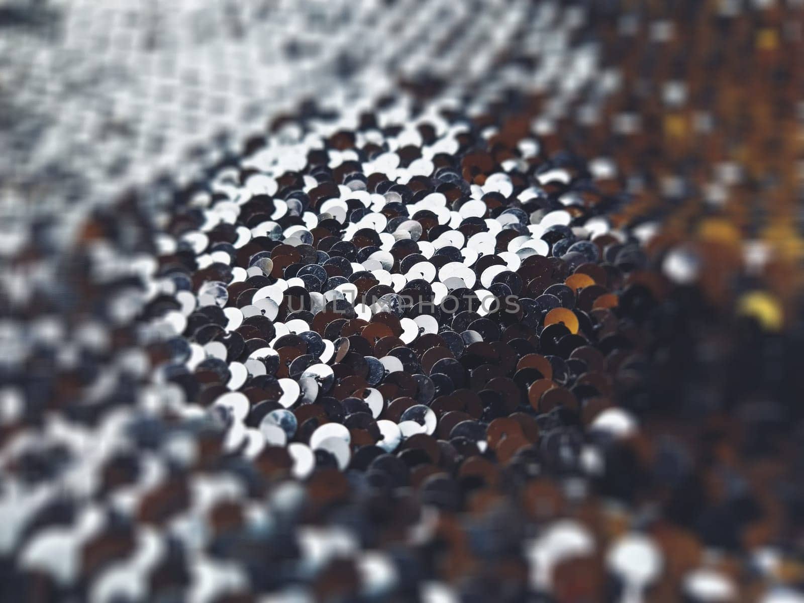 Sequin fabric. Black sequins with white-gray tint. Reflection of light on individual elements in a chaotic manner. Blurred circle background. Soft focus.