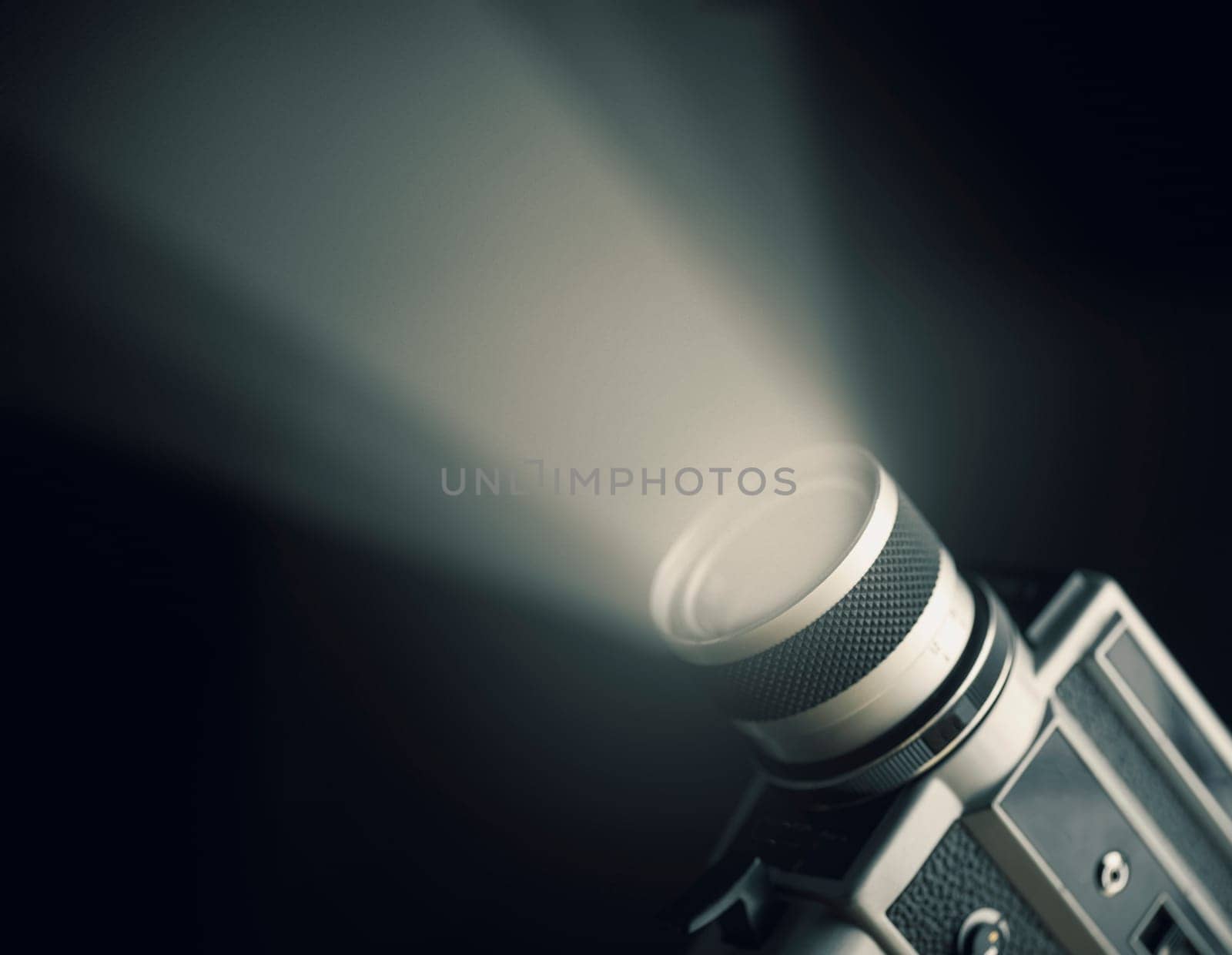 Vintage film camera super 8mm with spotlight over black background. Cinema art and entertainment industry.