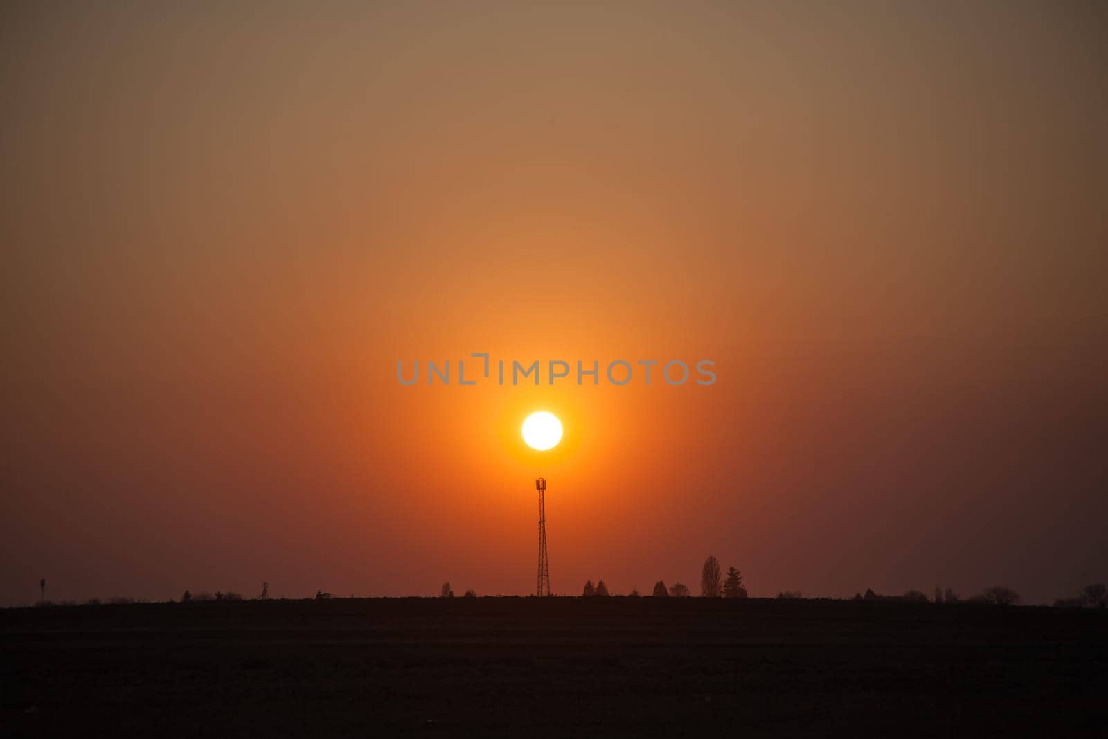 Red sunset over the field. Beautiful sunset in nature. Rural nature at sunset. Red sunset landscape