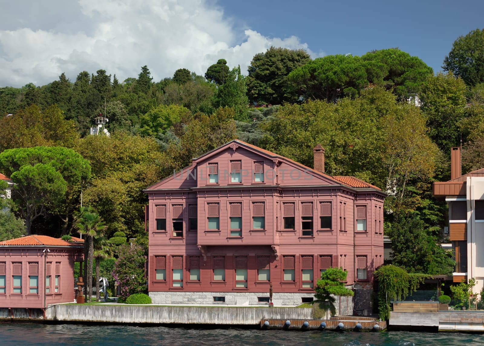 View from Bosphorus strait of the green mountains of the Asian side, with traditional red house and dense trees in a summer day, Istanbul, Turkey