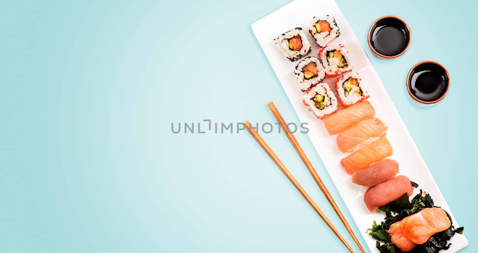 Sushi rolls set with salmon and tuna fish on light blue background from above. Top view of traditional japanese cuisine. Asian food restaurant menu modern design.