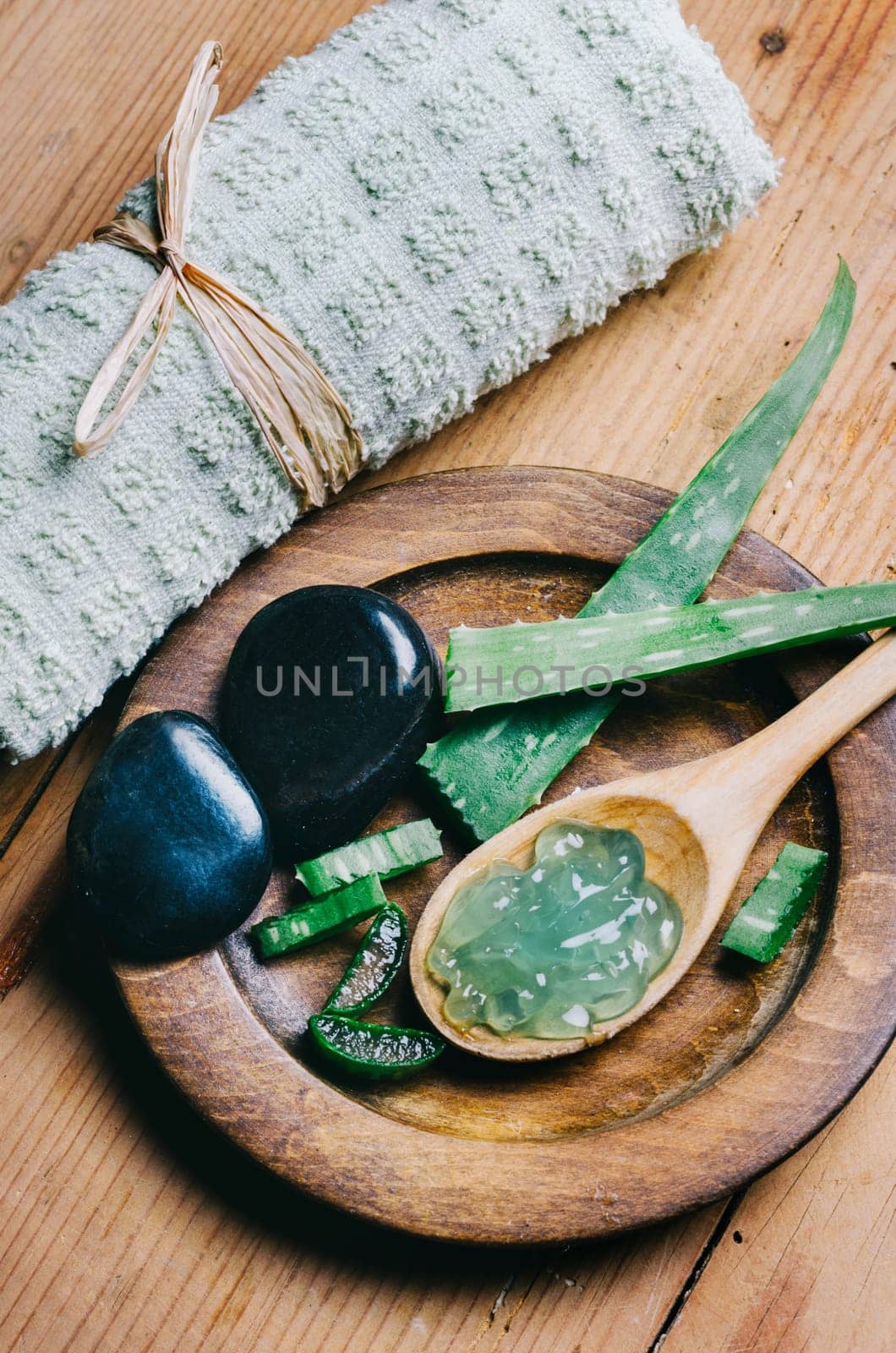 Top view of aloe vera spa and wellness cosmetic product for skin and beauty care. Herbal natural aromatherapy and zen massage stones on vintage wooden table. Asian alternative medicine treatment.
