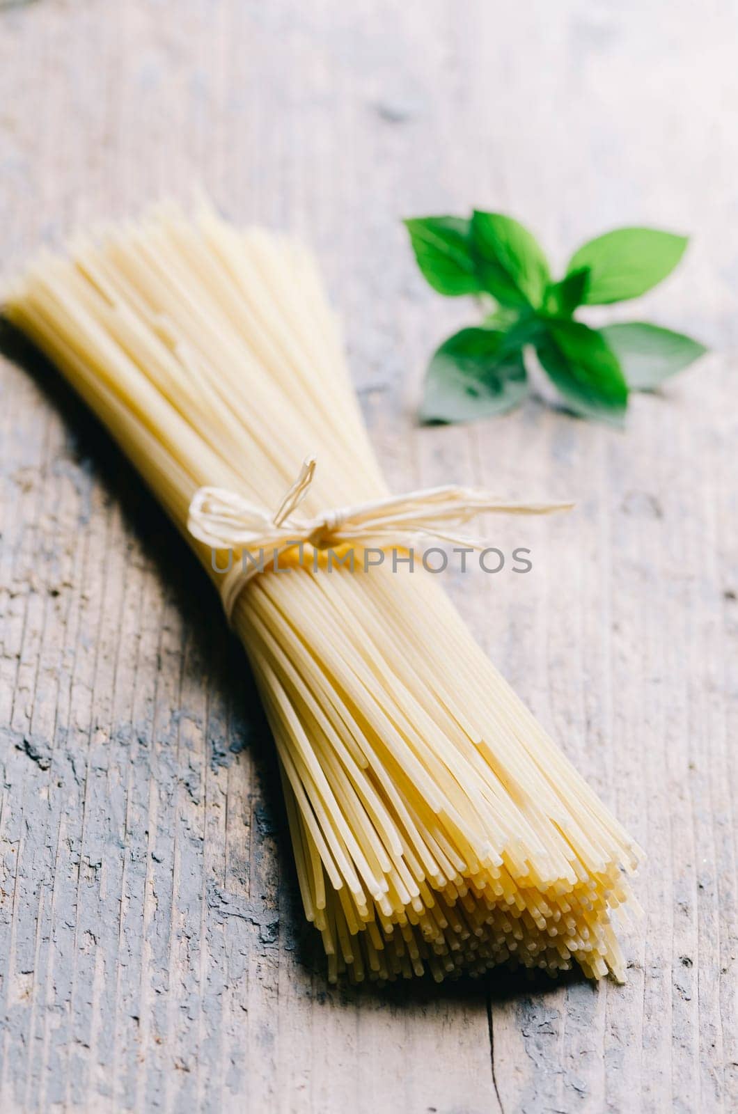 Italian raw pasta on rustic wooden table. Traditional long spaghetti dry.