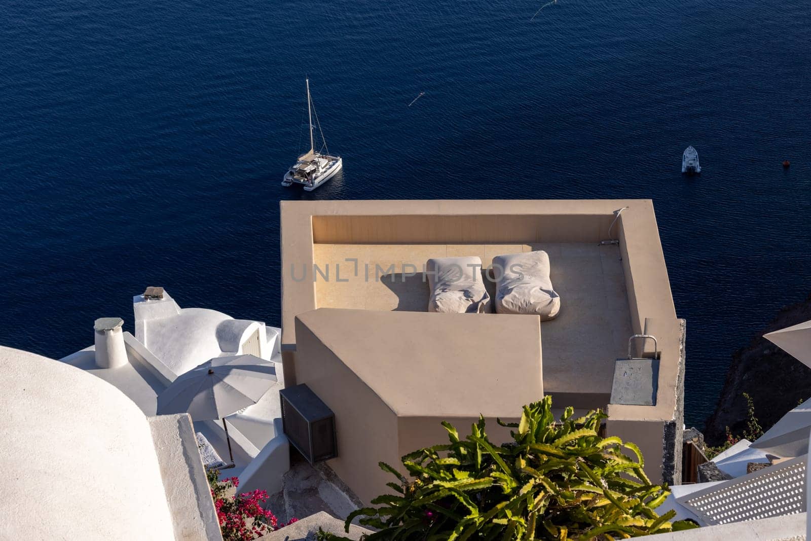 Oia, Santorini, Greece - June 28, 2021: Whitewashed houses with terraces and pools and a beautiful view in Oia on Santorini island, Greece