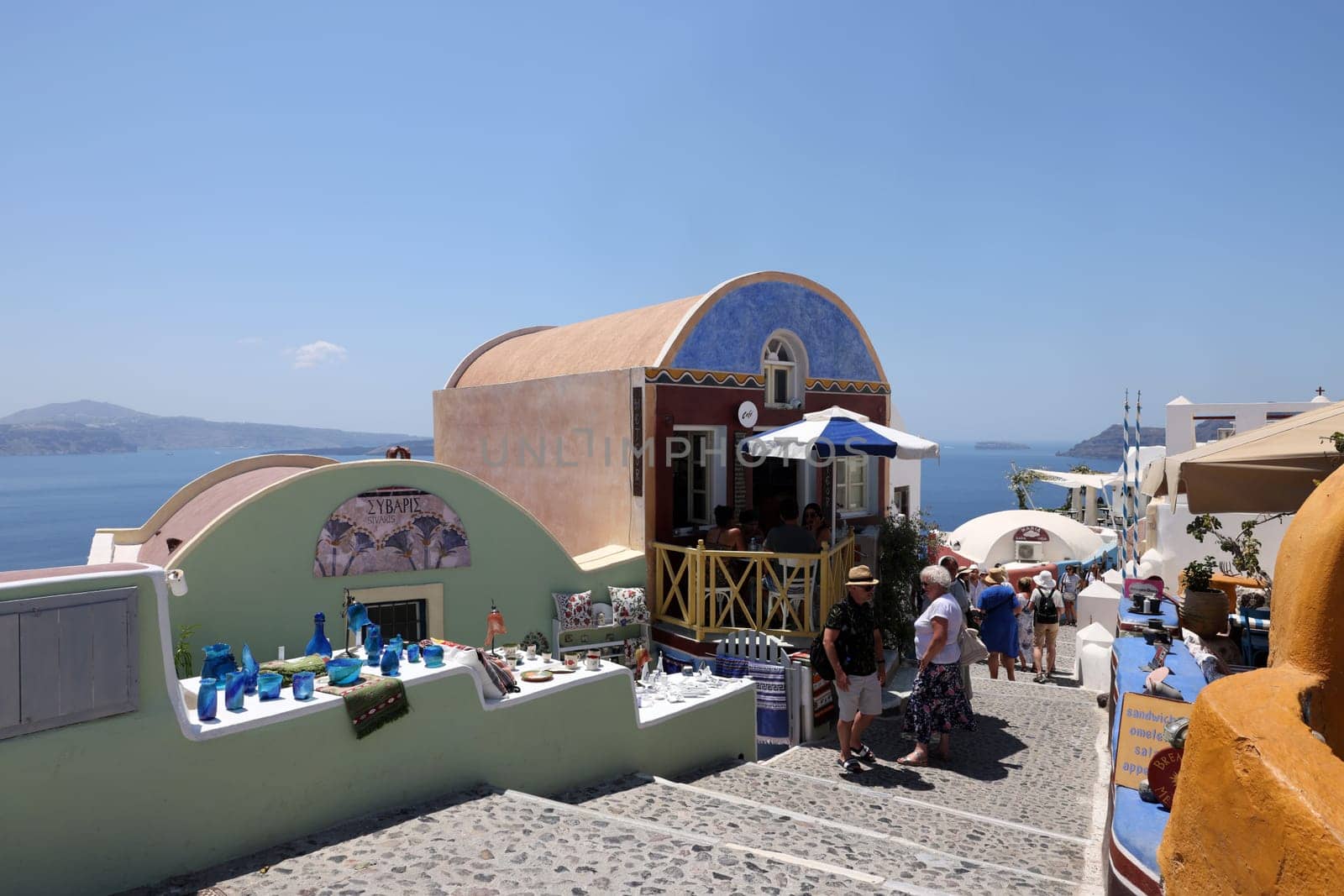 Oia, Santorini, Greece - July 3, 2021: Tourists while walking through the narrow streets of Oia, Santorini, Greece