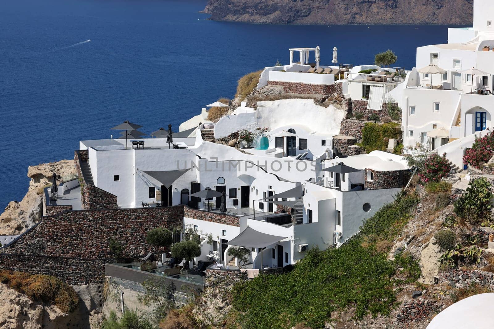Oia, Santorini, Greece - July 3, 2021: Whitewashed houses with terraces and pools and a beautiful view in Oia on Santorini island, Greece