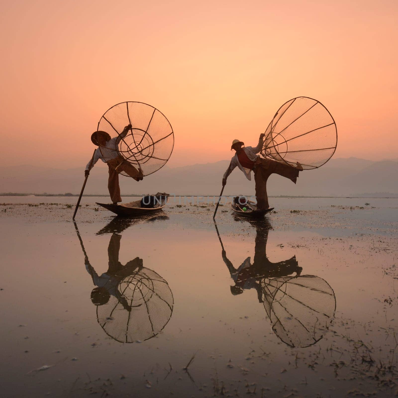 Fishermen at sunrise in the Landscape on the Inle Lake in the Shan State in the east of Myanmar in Southeastasia.