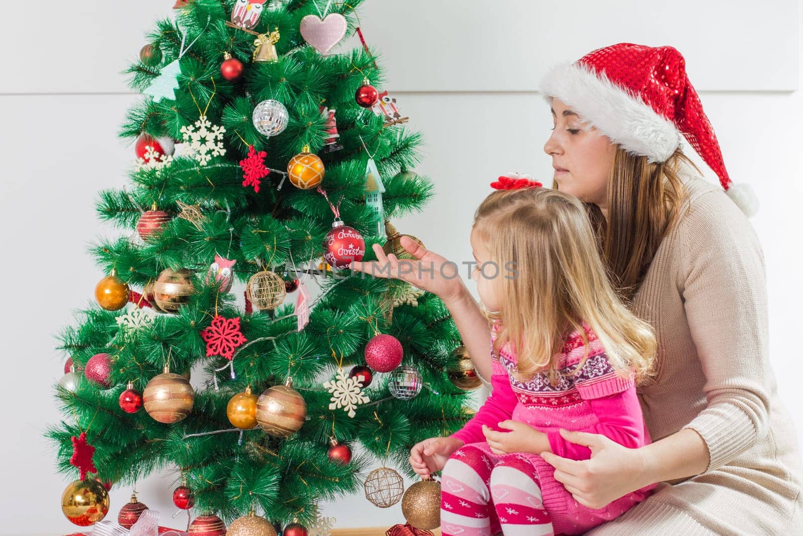 Christmas Happy Family mother and her two little daughters sitting on the floor and open Holidays Gift.