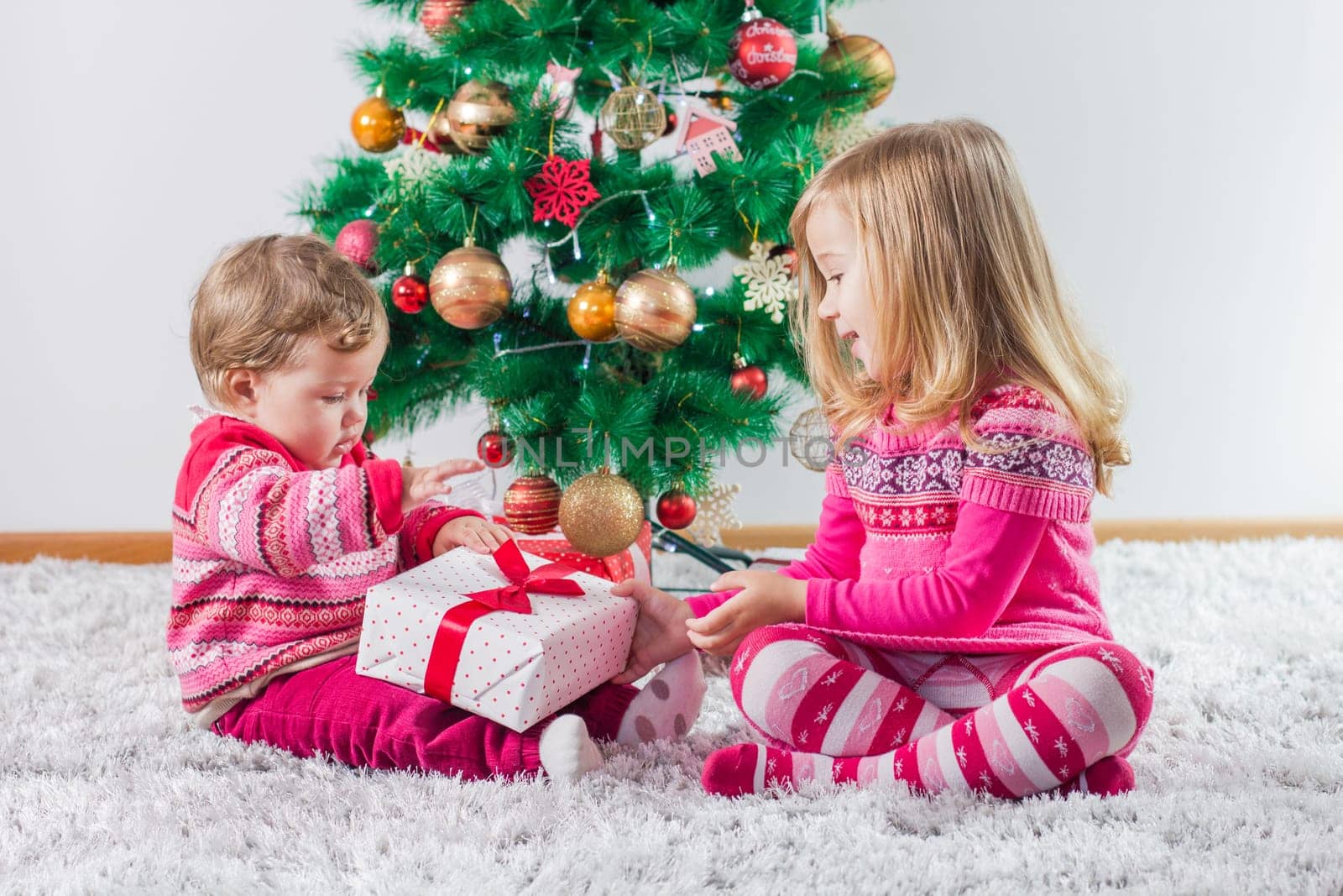 Happy children open Christmas presents on the floor and tree with New Year decoration at home.