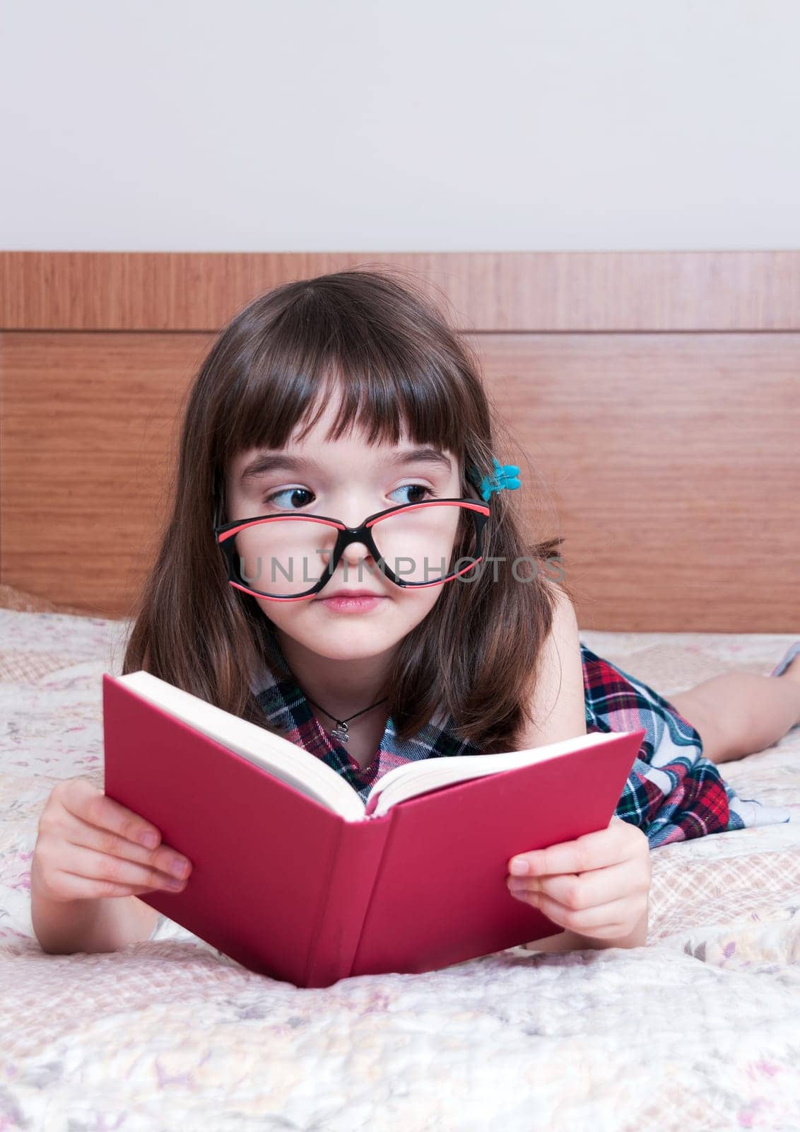 Little girl reading a book at home