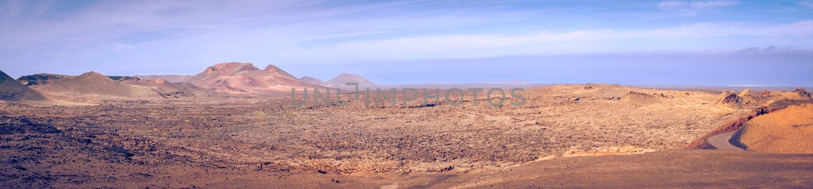 Wide panorama view on the desolate volcanic and moonlike landscape of Timanfaya National Park on Lanzarote, one of the Canary Islands of Spain and a famous travel destination for holidays