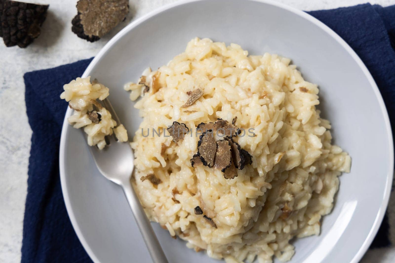Risotto with wild porcini mushrooms and black truffles from Italy served in a plate top view on a table. Eating Italian gourmet cousine
