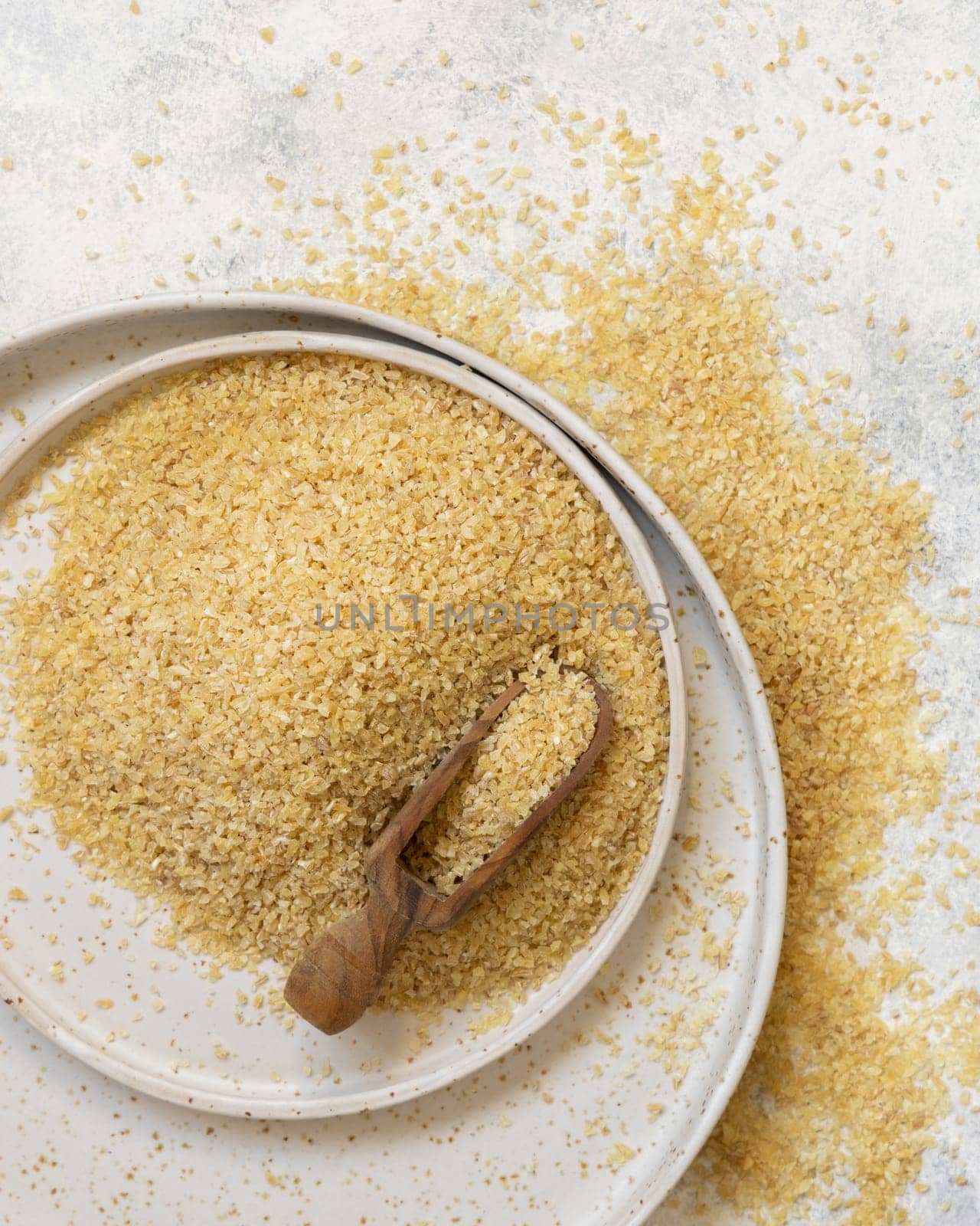 Pile of Dry uncooked bulgur wheat grain with a scoop on a plate top view. Vegetarian and Vegan, Mediterranean and Middle Eastern cuisine. Healthy lifestyle