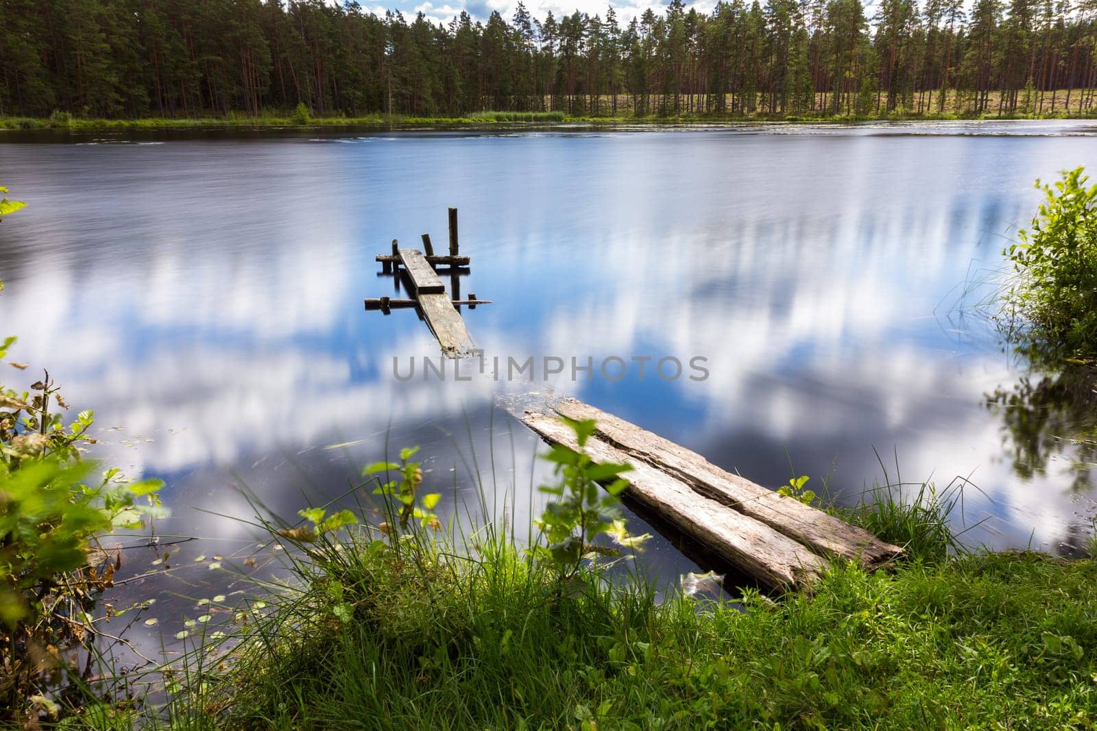 A small mesa lake with a boardwalk. Reflection of clouds in it.