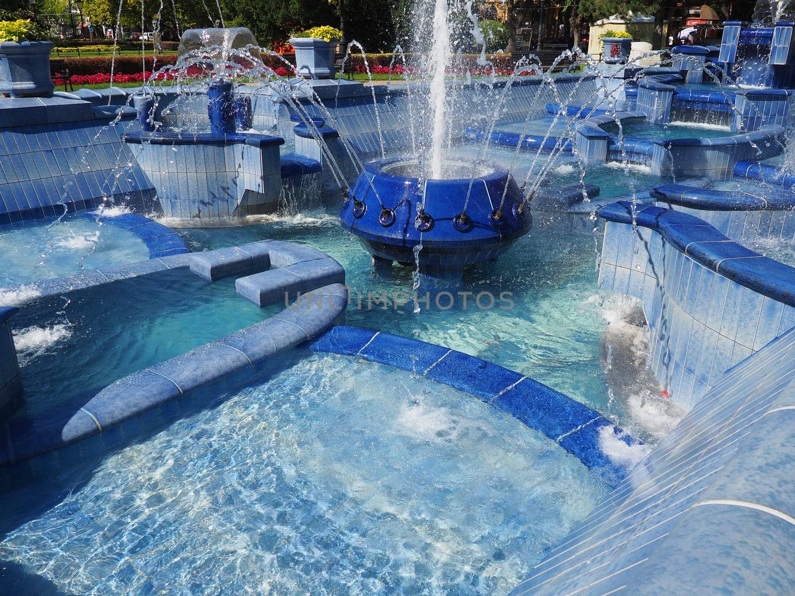 Subotica, Serbia September 12, 2021. Blue fountain in the square next to the Town Hall. Blue ceramic parts with monograms. A working fountain with splashing water. Summer sunny day by the blue water.