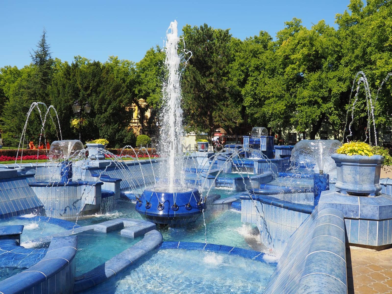 Subotica, Serbia September 12, 2021. Blue fountain in the square next to the Town Hall. Blue ceramic parts with monograms. A working fountain with splashing water. Summer sunny day by the blue water.