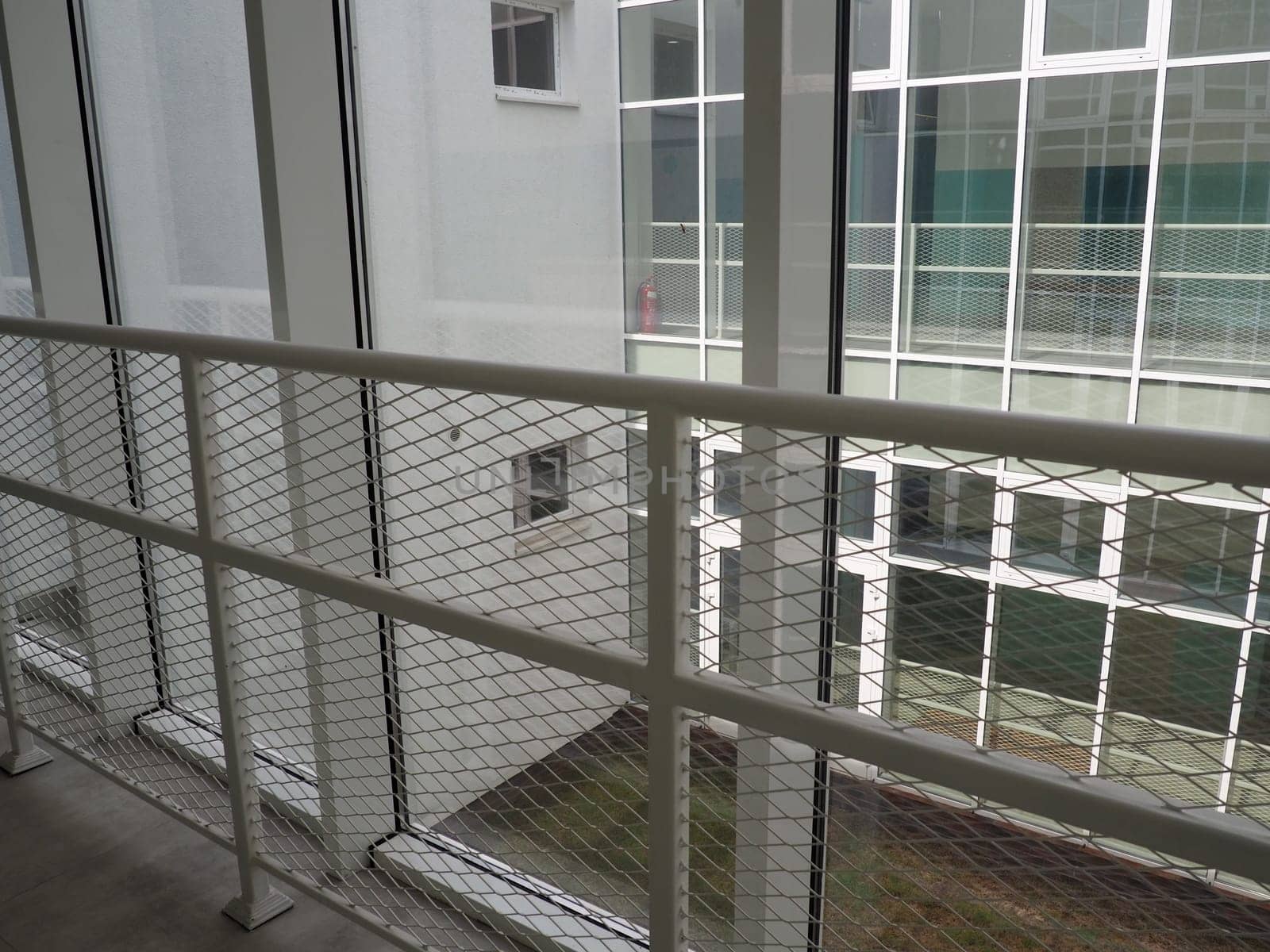 New white frames and windows. Metal fence for the safety of schoolchildren. New modern school. View from the window to the opposite wall and windows. Security systems. Internal office interior