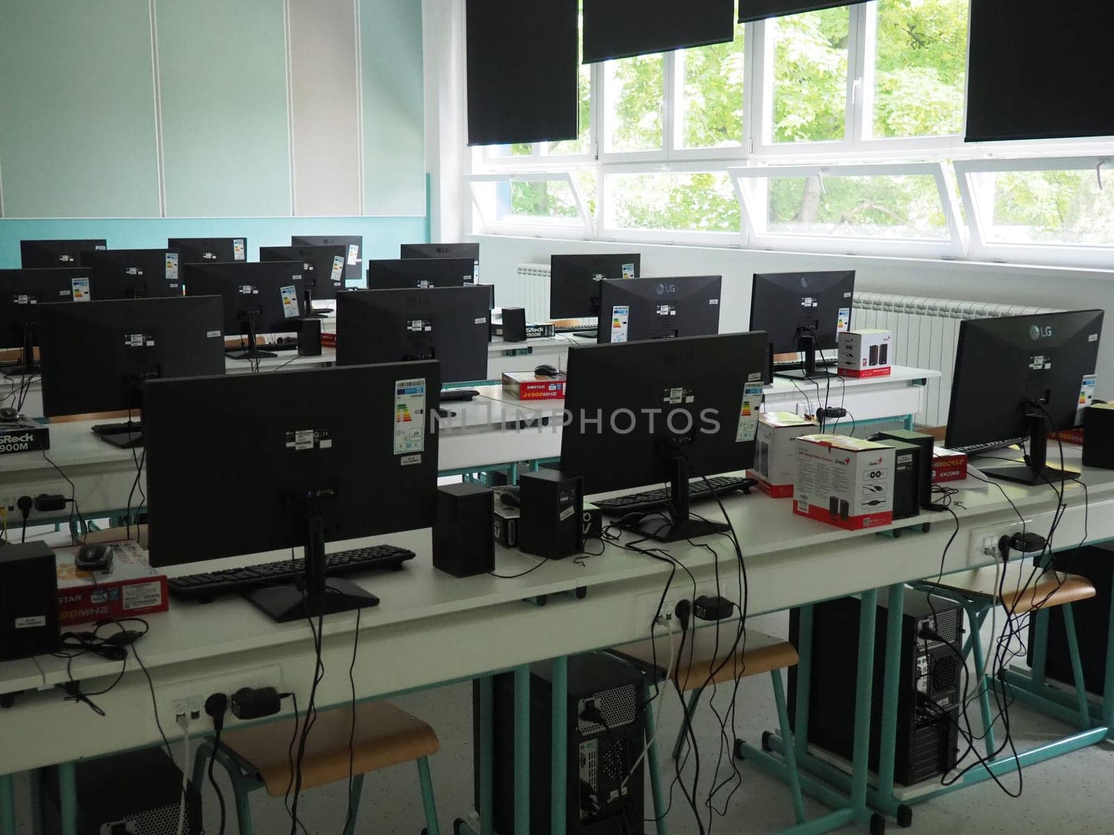 Sremska Mitrovica, Serbia, May 15, 2021 Group of computer neatly placed in a computer lab. Computers, monitors, wires in the modern classroom of the new school. School desks for pupils and students.