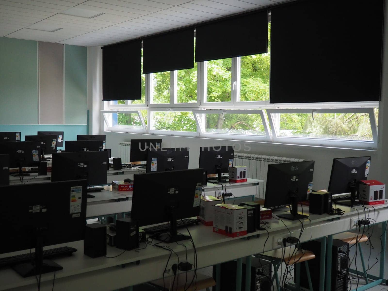 Sremska Mitrovica, Serbia, May 15, 2021 Group of computer neatly placed in a computer lab. Computers, monitors, wires in the modern classroom of the new school. School desks for pupils and students.