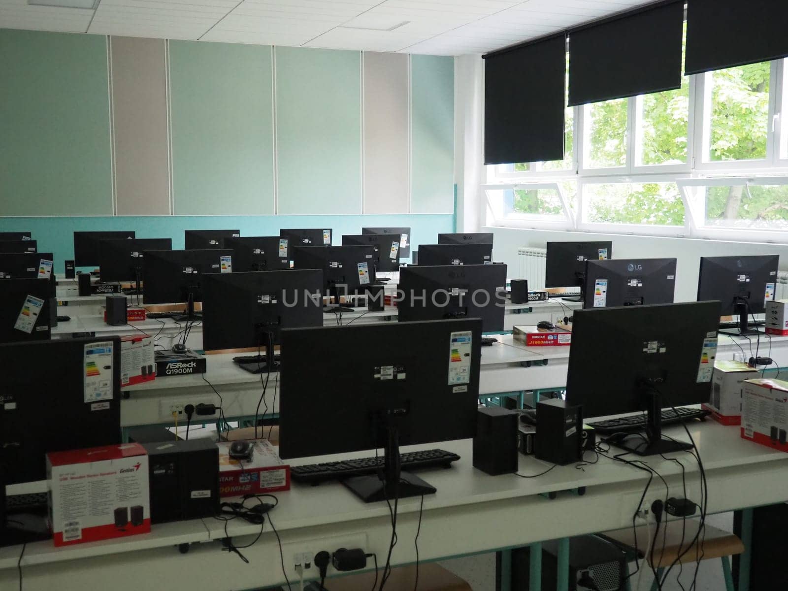 Sremska Mitrovica, Serbia, May 15, 2021 Group of computer neatly placed in a computer lab. Computers, monitors, wires in the modern classroom of the new school. School desks for pupils and students.