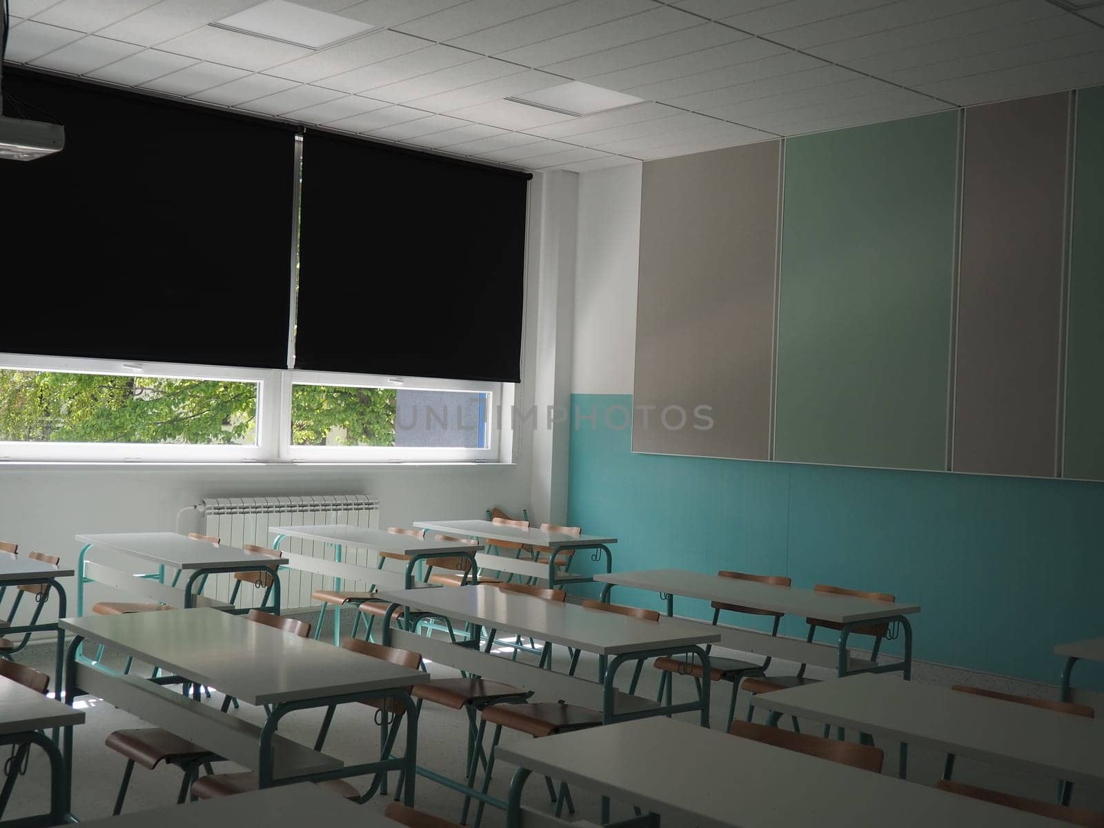 Lecture room with empty seats. Business seminar education. Modern new school. White furniture. Large windows with blackout curtains or blinds. Empty school classroom. Furniture and school equipment.