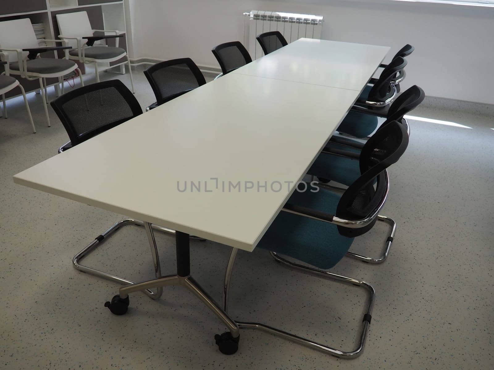 table and chairs in the meeting room or in the auditorium. Library, office, or premises in an official institution or bank. There is no one at the table. White, black and gray paints in the interior.