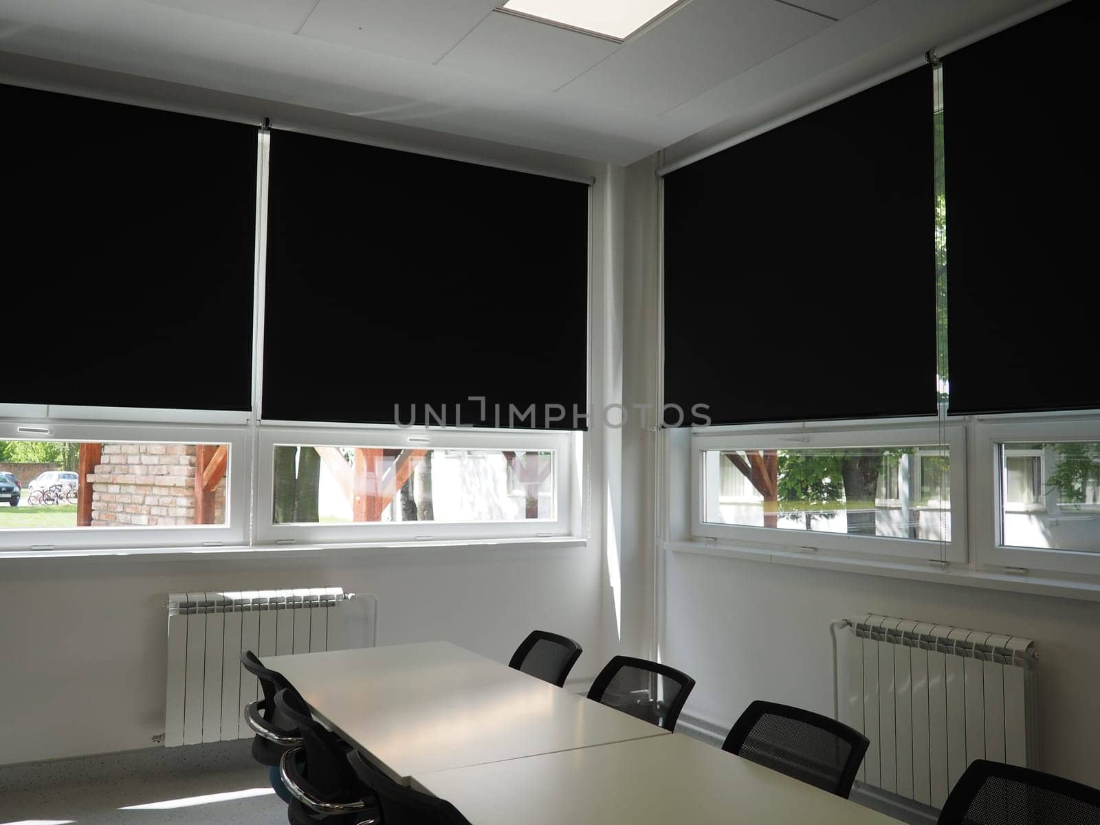 table and chairs in the meeting room in the office, in the classroom or in the library hall. White, black and gray paints in the interior. Black blinds for darkening the room. Modern interior design.