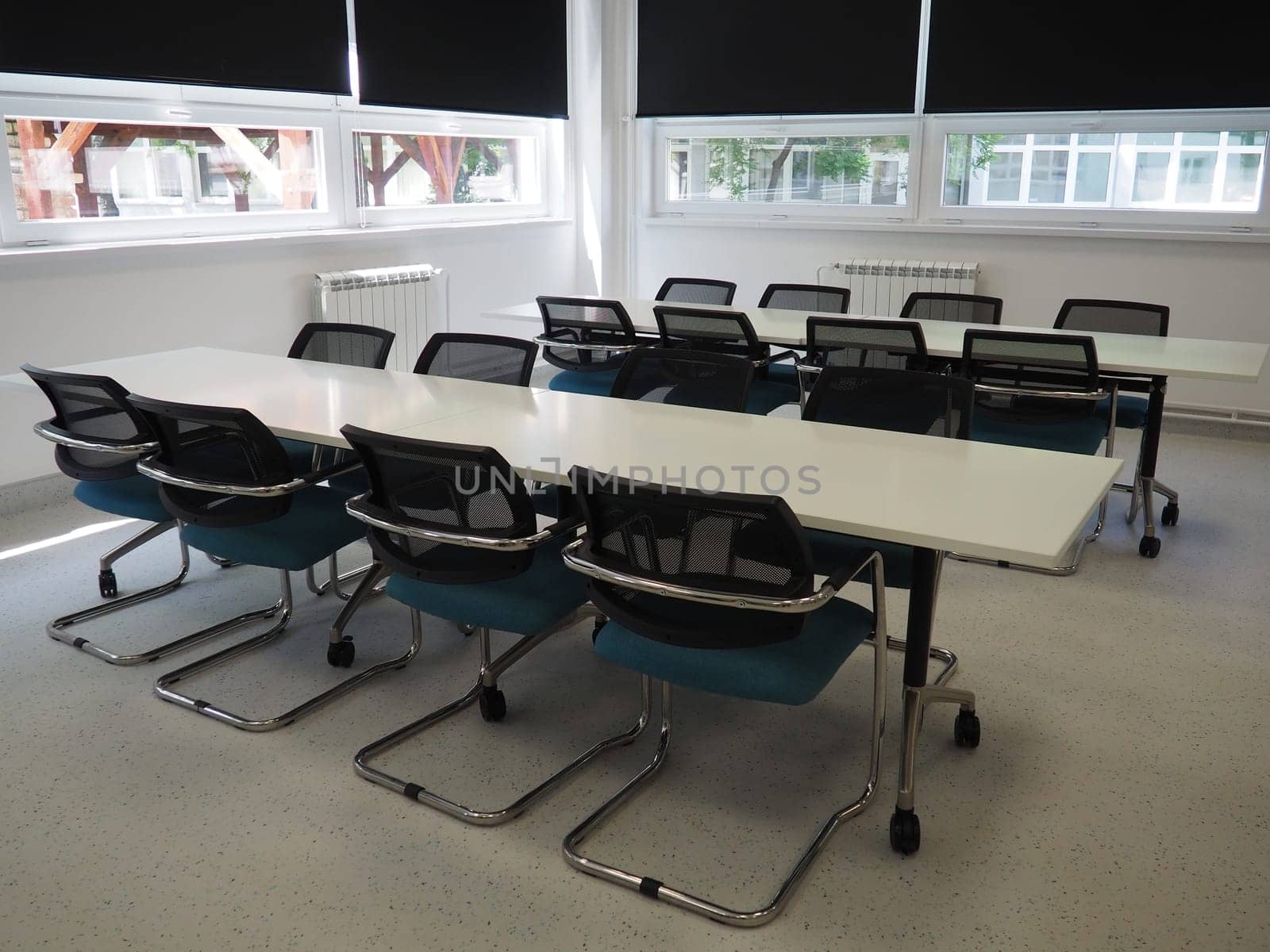 table and chairs in the meeting room in the office, in the classroom or in the library hall. White, black and gray paints in the interior. Black blinds for darkening the room. Modern interior design.
