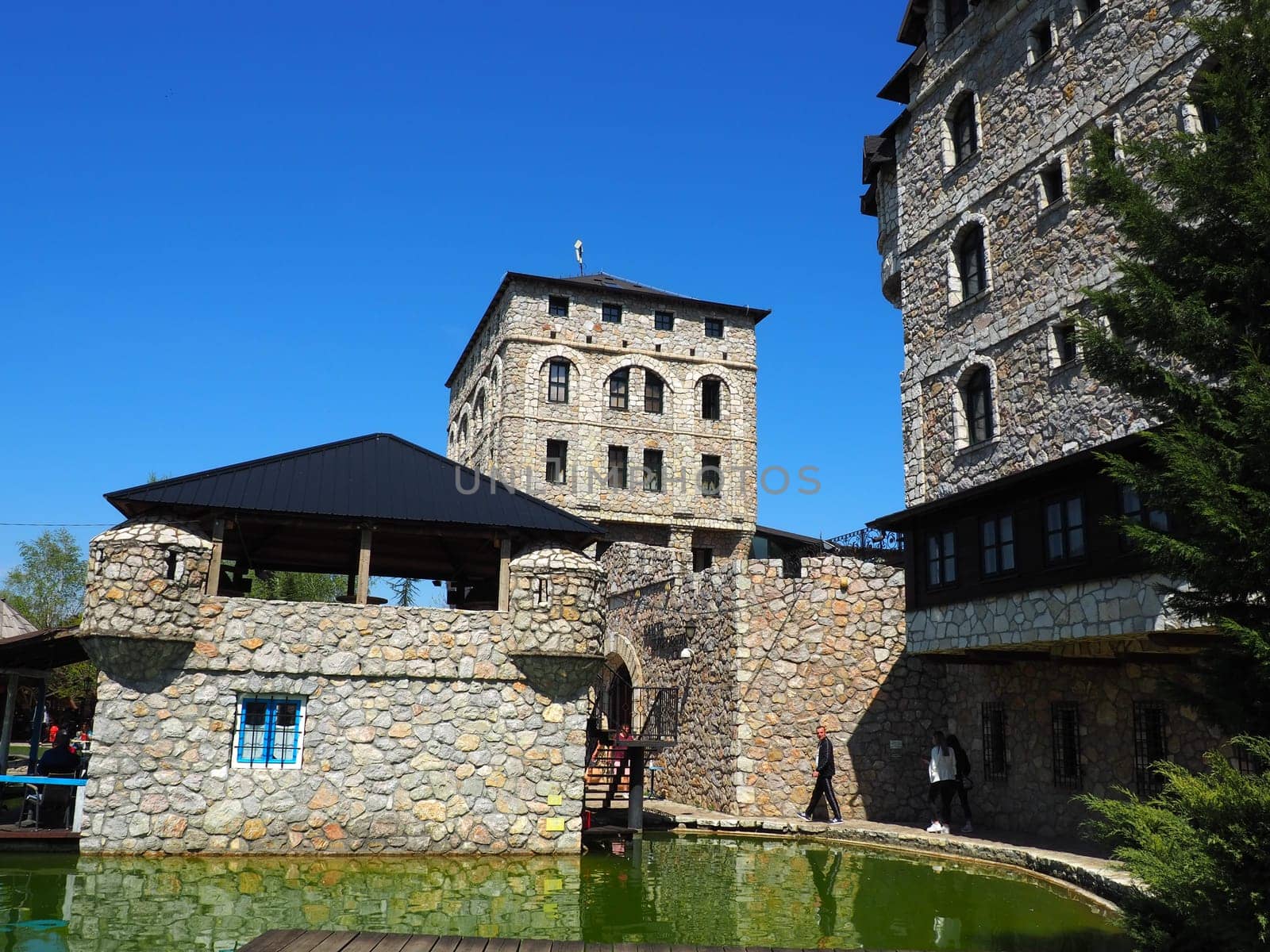 Stanisici, Bijelina, Republika Srpska, Bosnia and Herzegovina April 25 2021 Ethno village, tourism and attractions. Stone and wooden buildings of the hotel. People visit restaurant, traditional houses