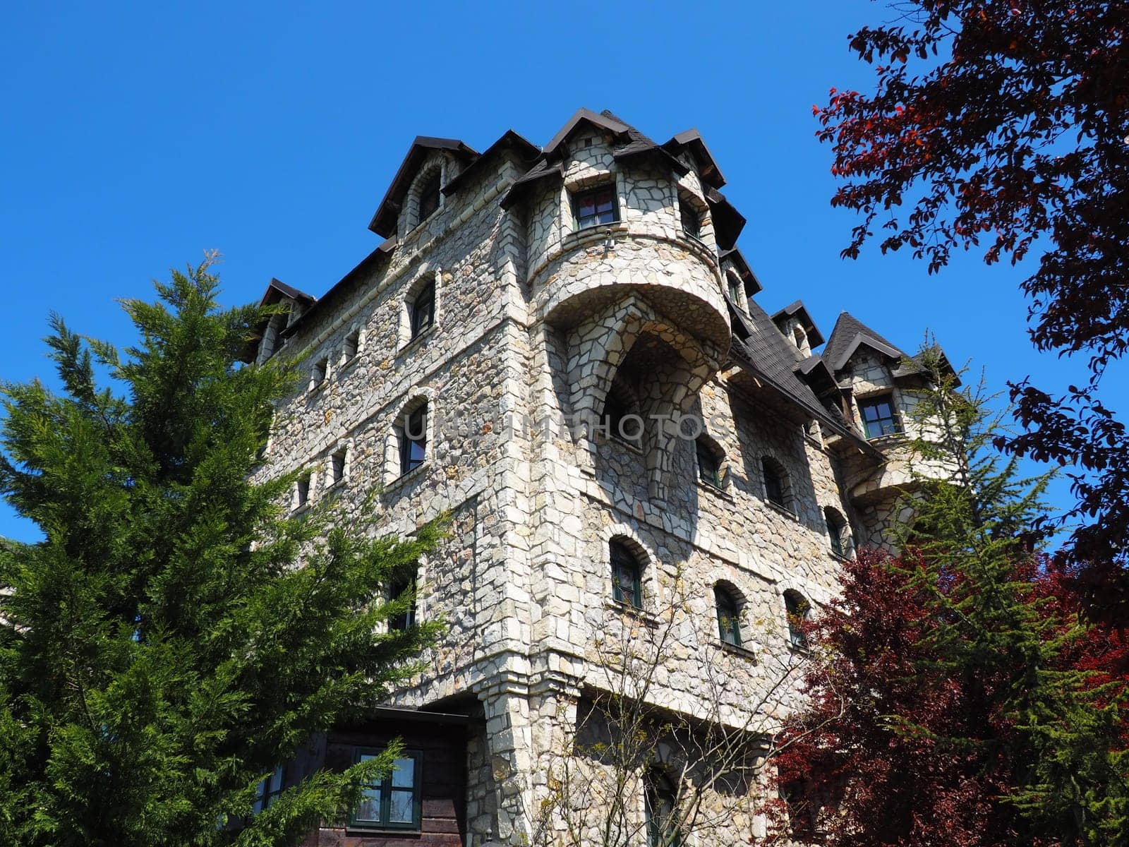 Ethno village, tourism and attractions. Stone and wooden buildings of the hotel. People visit restaurant, traditional houses.