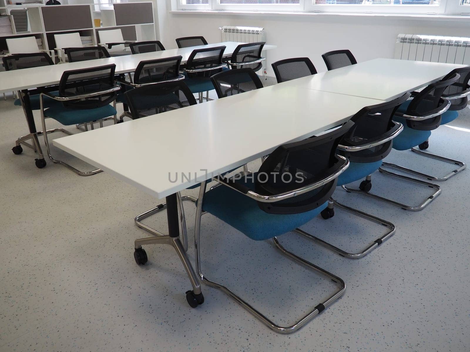 table and chairs in the meeting room or in the auditorium. Library, office, or premises in an official institution or bank. There is no one at the table. White, black and gray paints in the interior.