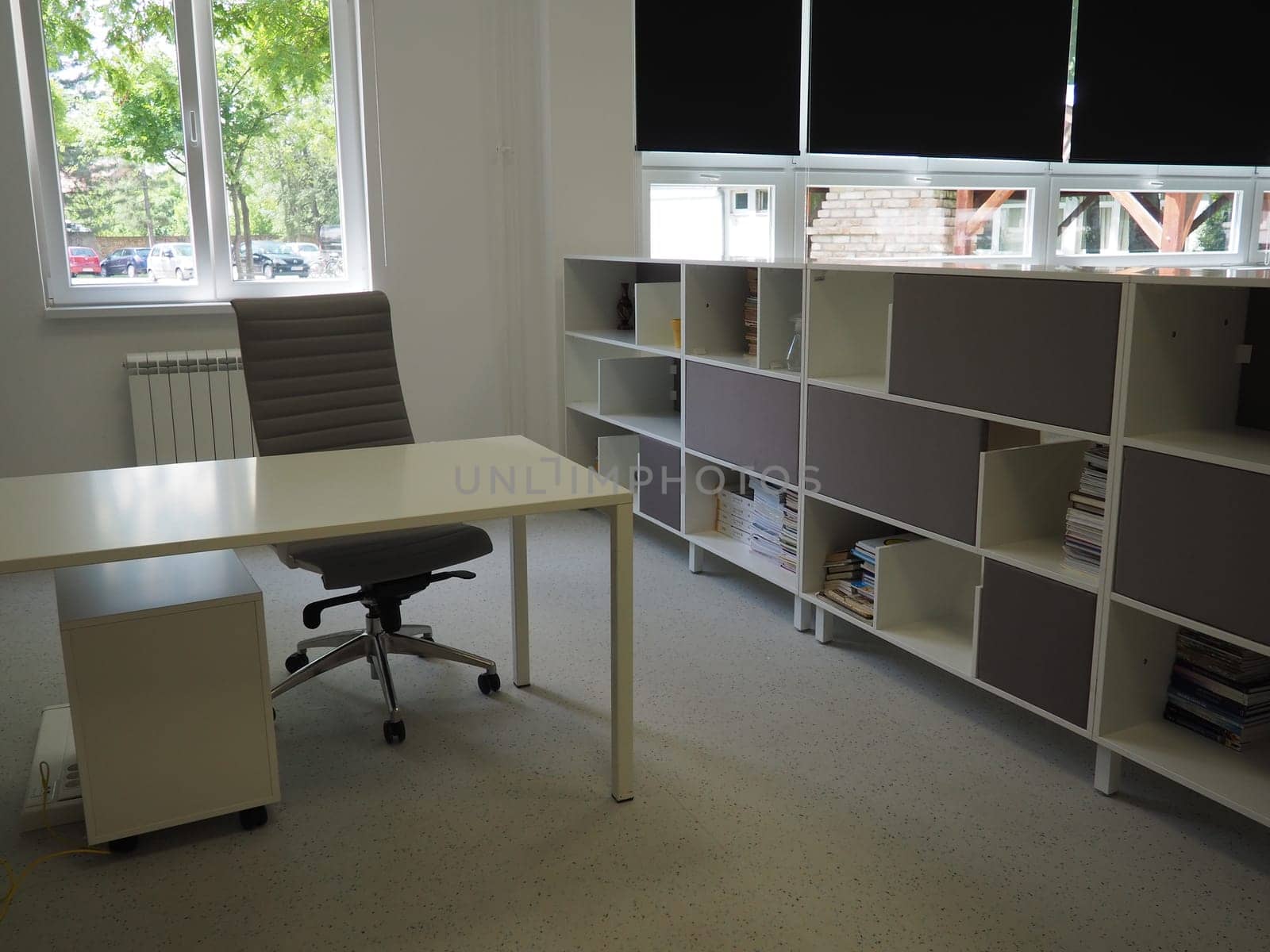 table and chairs in the meeting room in the office, in the classroom or in the library hall. White, black and gray paints in the interior. Black blinds for darkening the room. Modern interior design.