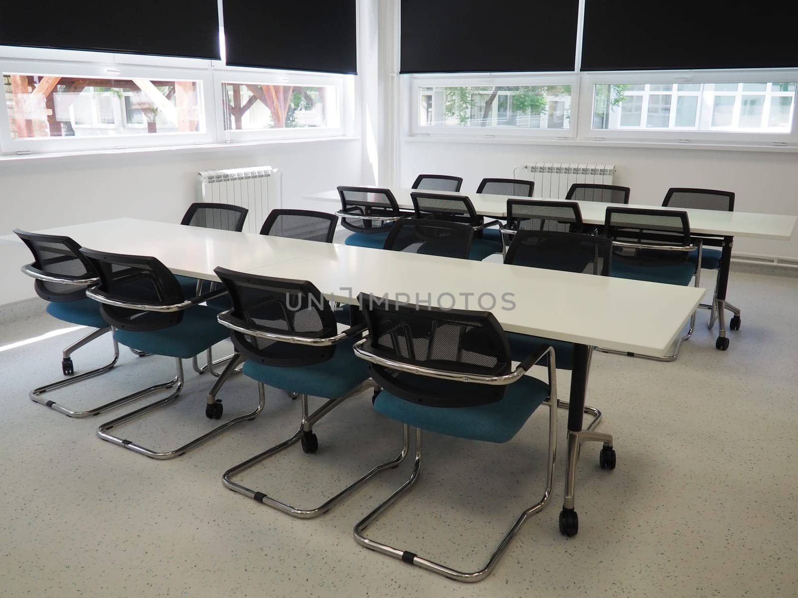 table and chairs in the meeting room in the office, in the classroom or in the library hall. White, black and gray paints in the interior. Black blinds for darkening the room. Modern interior design.