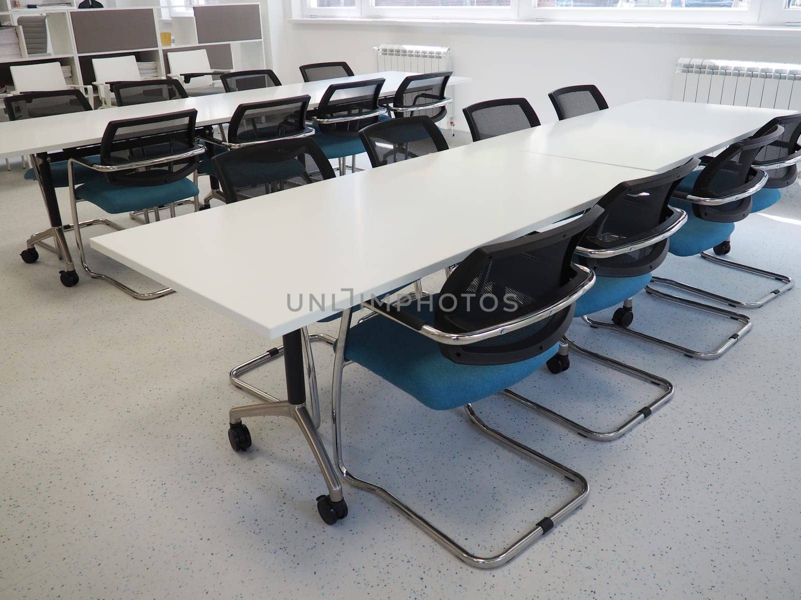 table and chairs in the meeting room or in the auditorium. Library, office, or premises in an official institution or bank. There is no one at the table. White, black and gray paints in the interior.