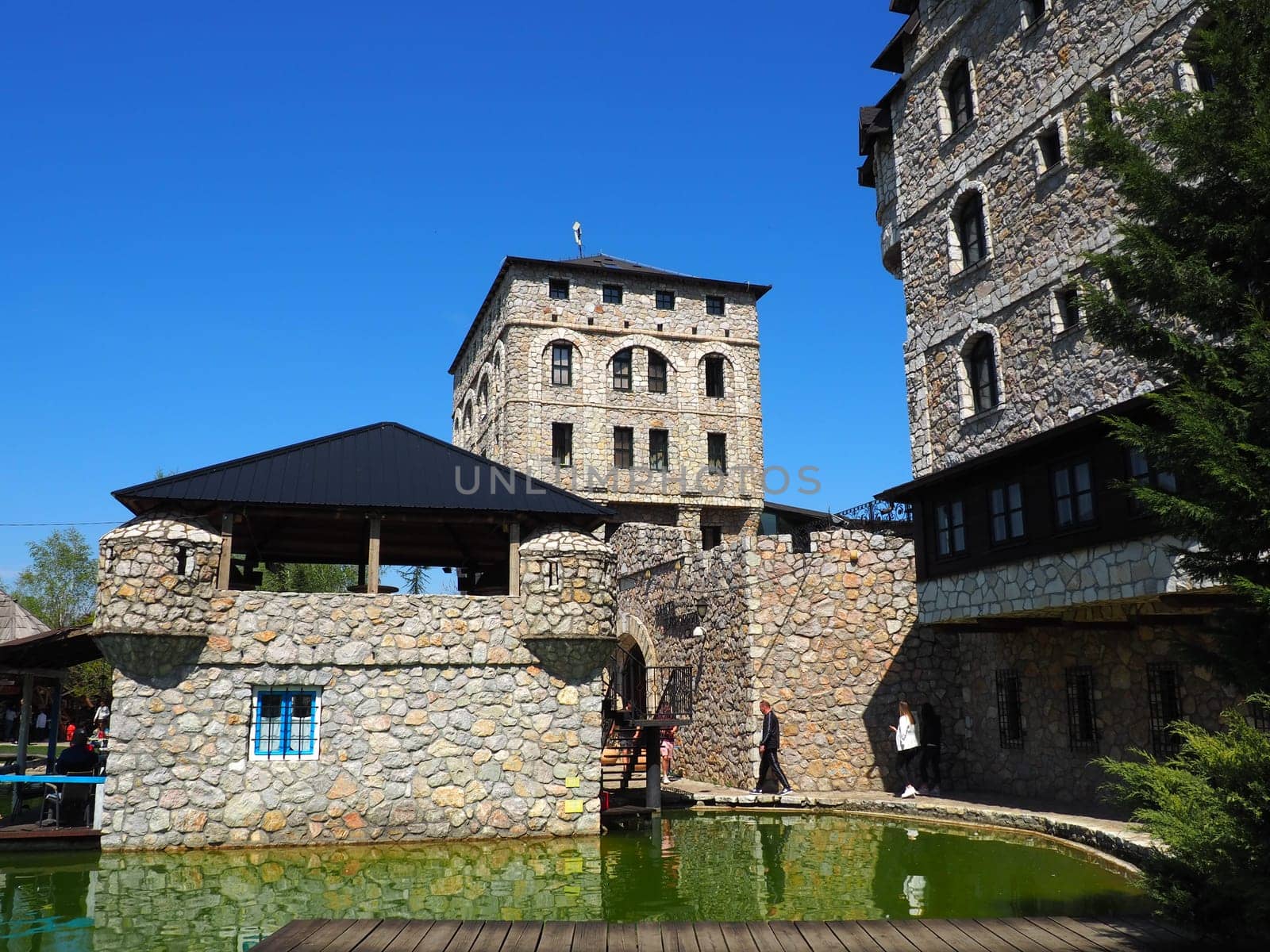 Stanisici, Bijelina, Republika Srpska, Bosnia and Herzegovina April 25 2021 Ethno village, tourism and attractions. Stone and wooden buildings of the hotel. People visit restaurant, traditional houses