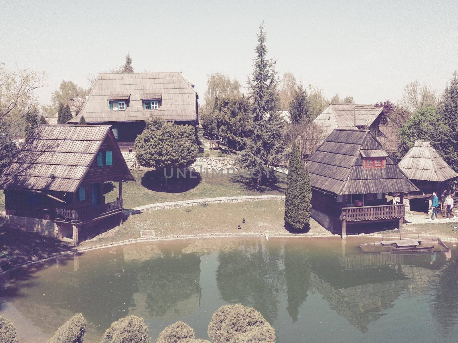 Stanisici, Bijelina, Bosnia and Herzegovina. April 25, 2021 Ethno-village, traditional village houses made of logs, Bosnian style of construction in the highlands. Lake with water. Wooden architecture