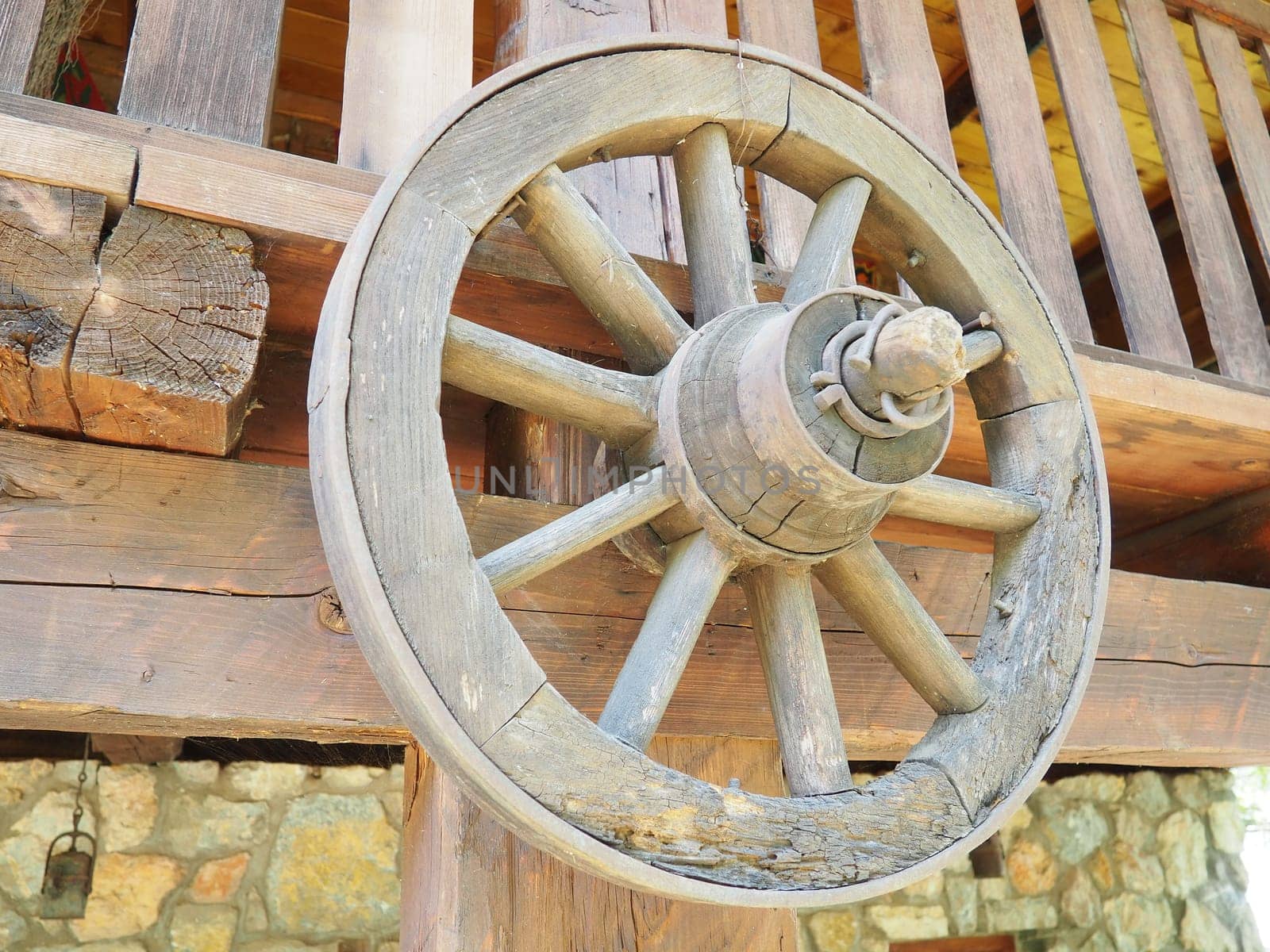 Wooden wheel from a cart. Decorative wheels for decorating lawns, exteriors and rustic interiors. A round homemade wheel hangs on the wall. Retro or vintage style. Life in the countryside.