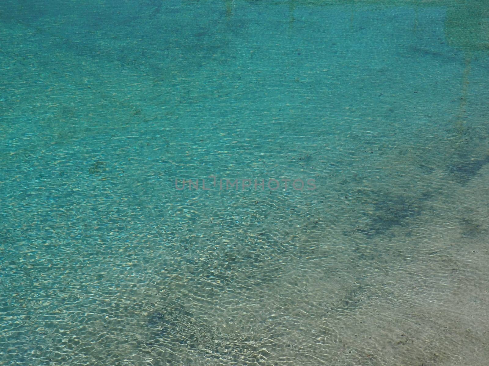 blue and turquoise water. Clear sea water with waves and sun glare. The bottom is visible.