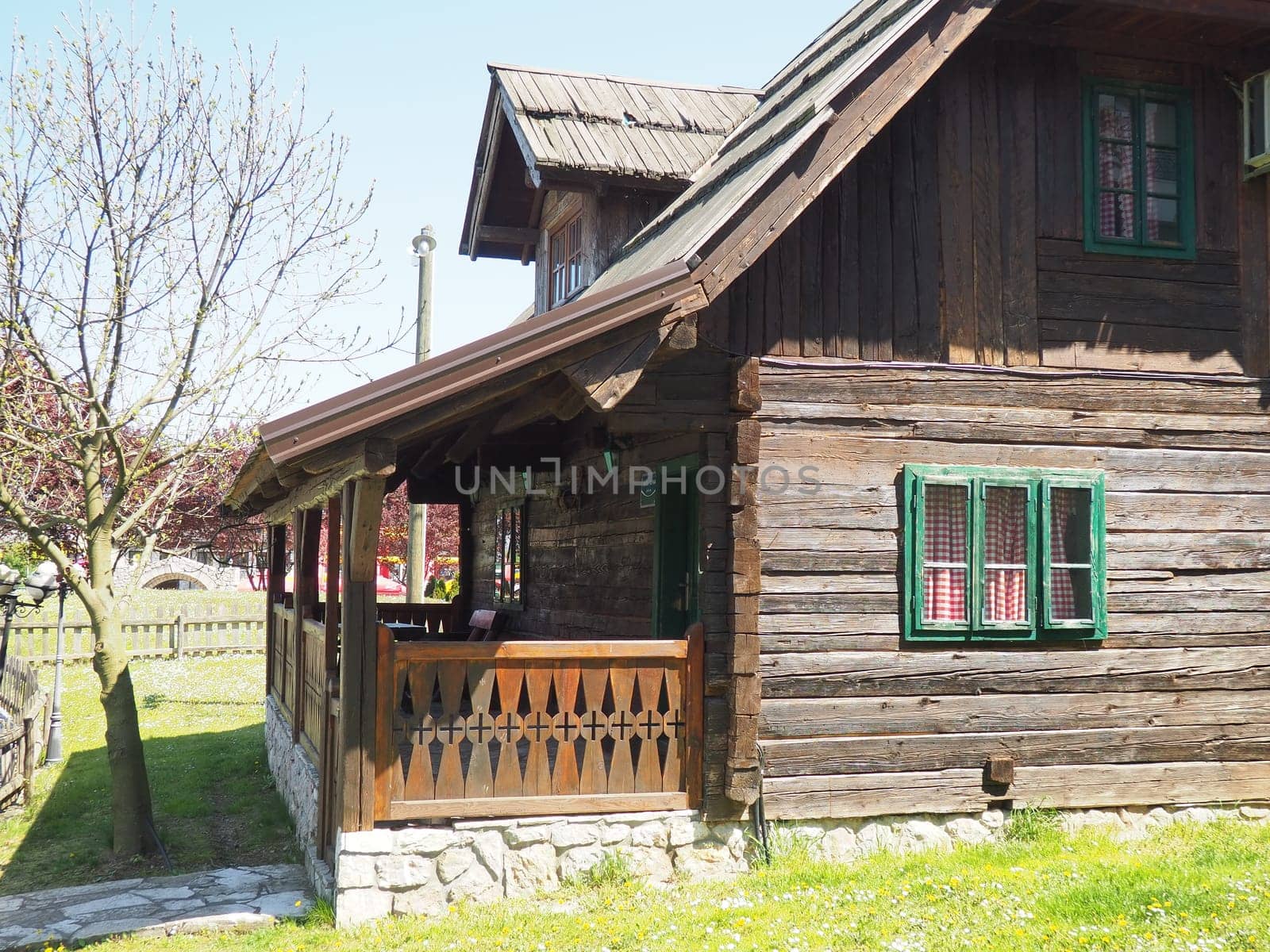 19th century Bosnian mountain traditional dwelling. Restored ethno building, Wooden deck, kitchen checkered curtains.
