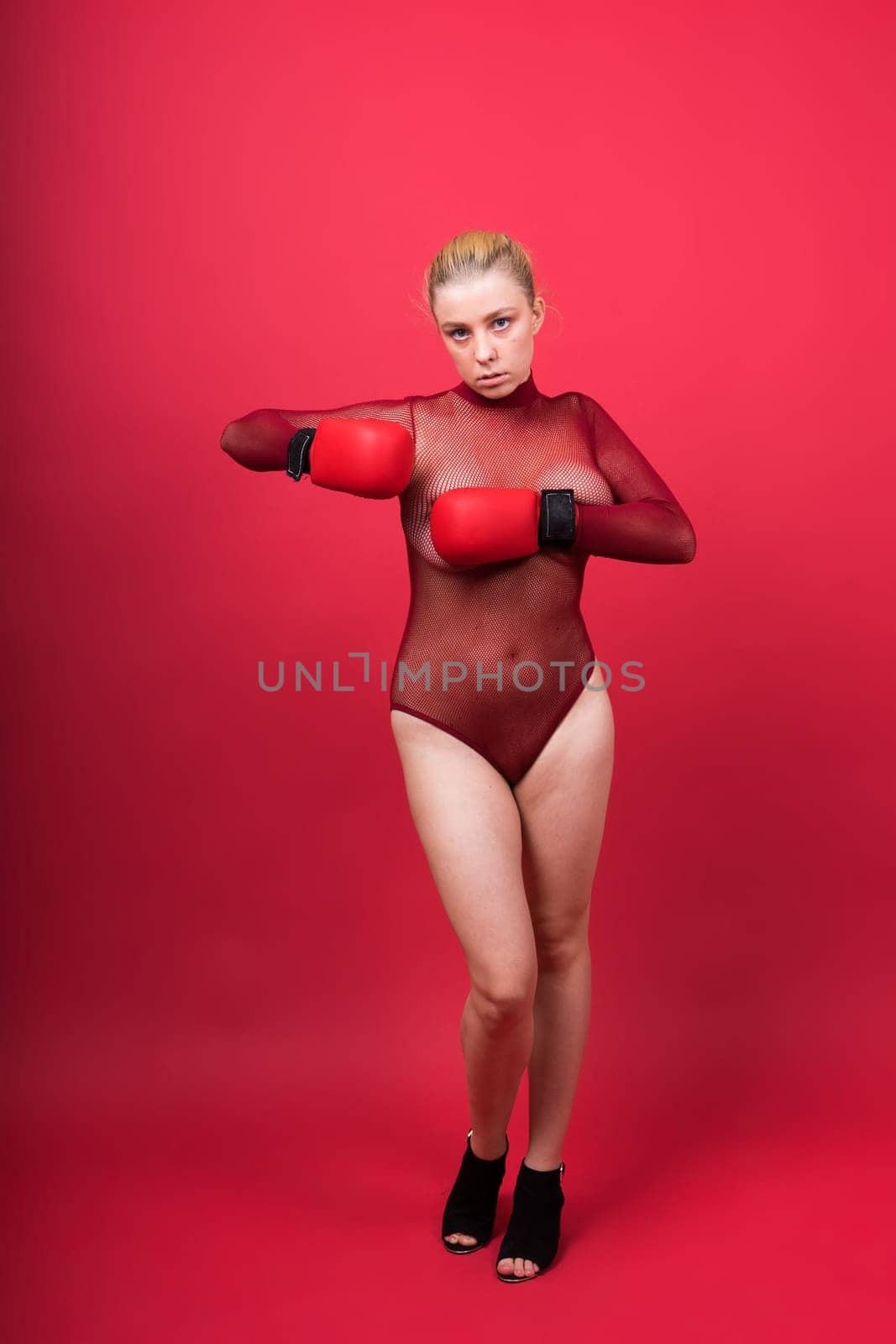 Image of seductive young woman boxer posing isolated on yellow red background in boxing gloves.
